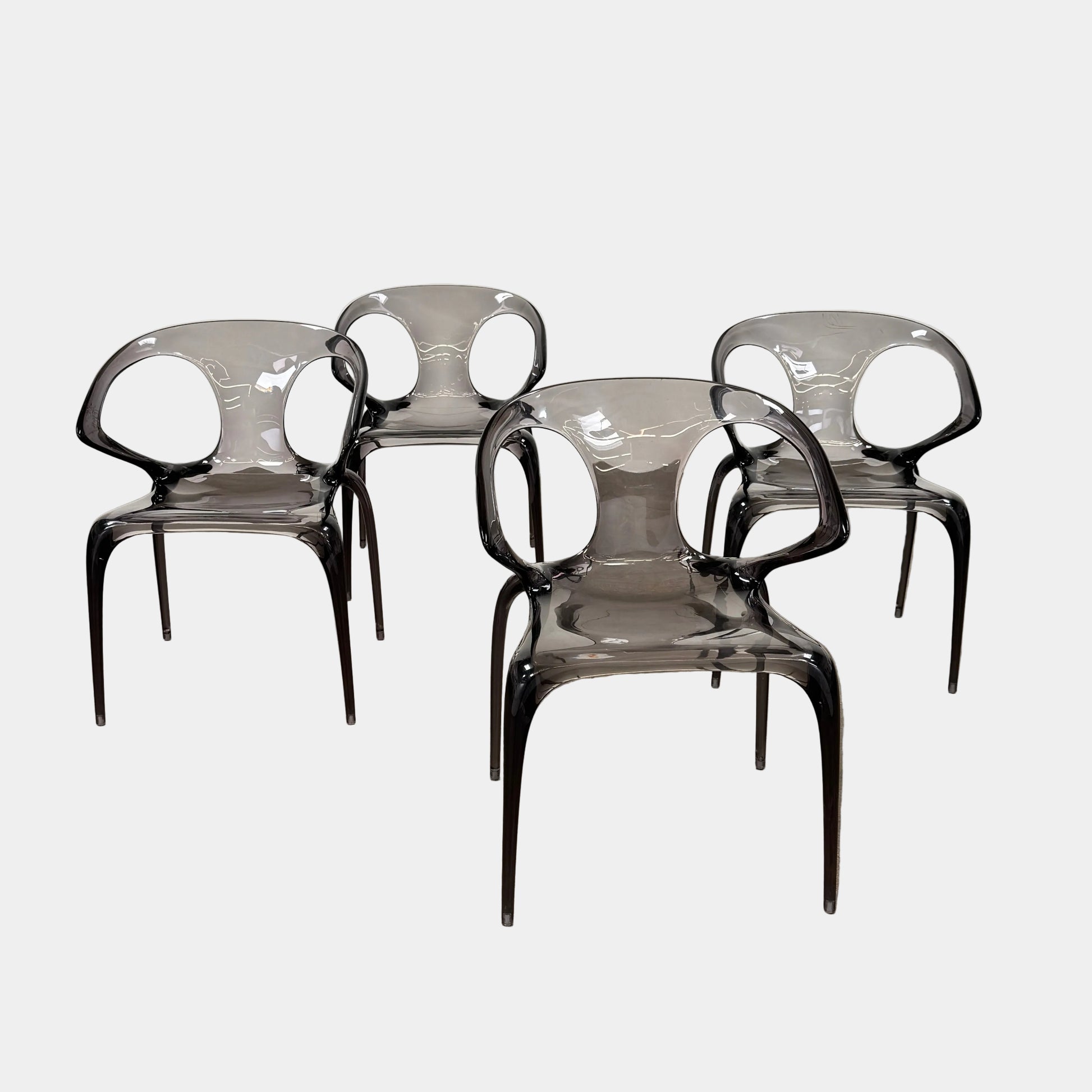Four stackable Roche Bobois Ava Transparent Chairs (Set of 4) with rounded backs and armrests are arranged in two rows against a plain white background, showcasing the sleek modern style of Roche Bobois.