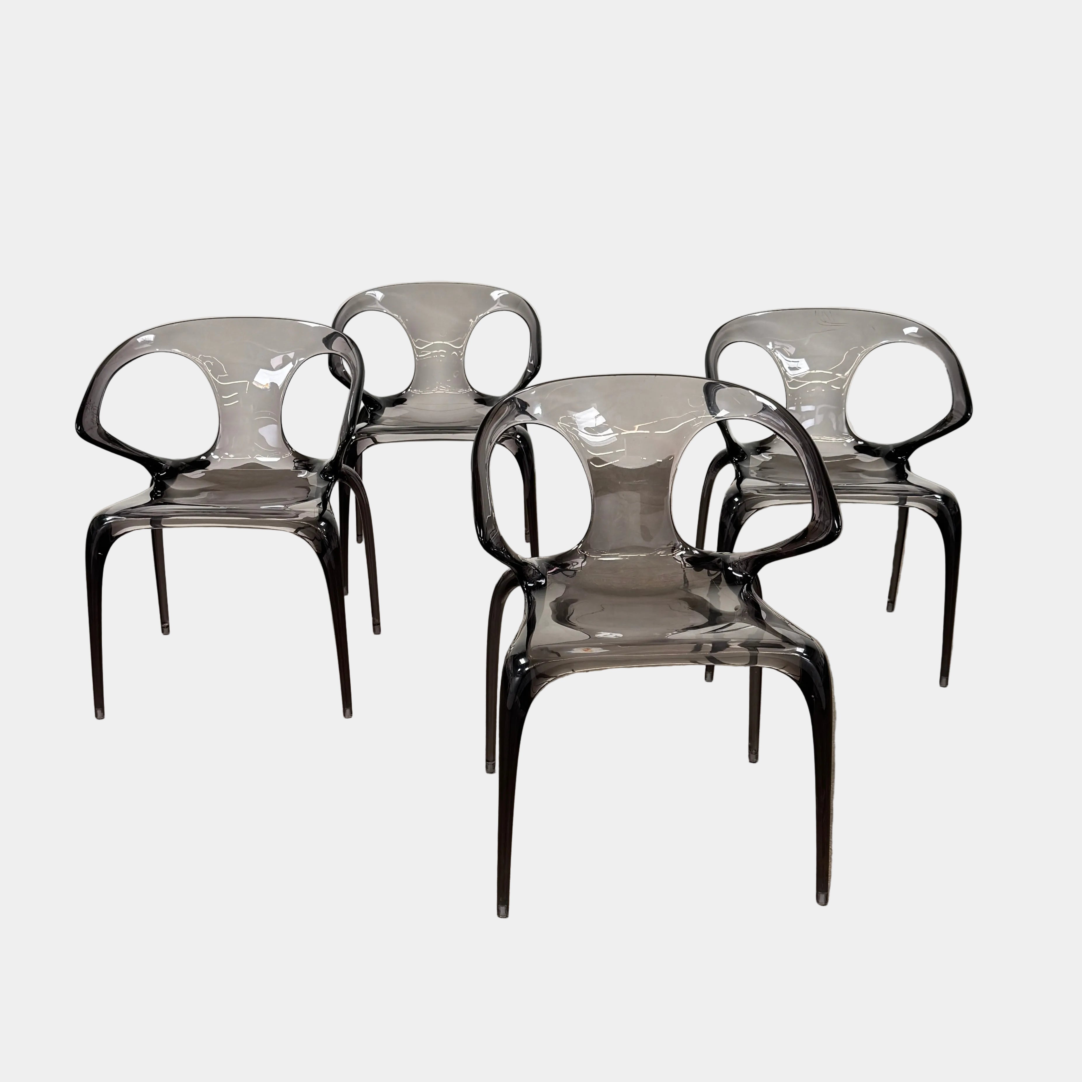 Four stackable Roche Bobois Ava Transparent Chairs (Set of 4) with rounded backs and armrests are arranged in two rows against a plain white background, showcasing the sleek modern style of Roche Bobois.