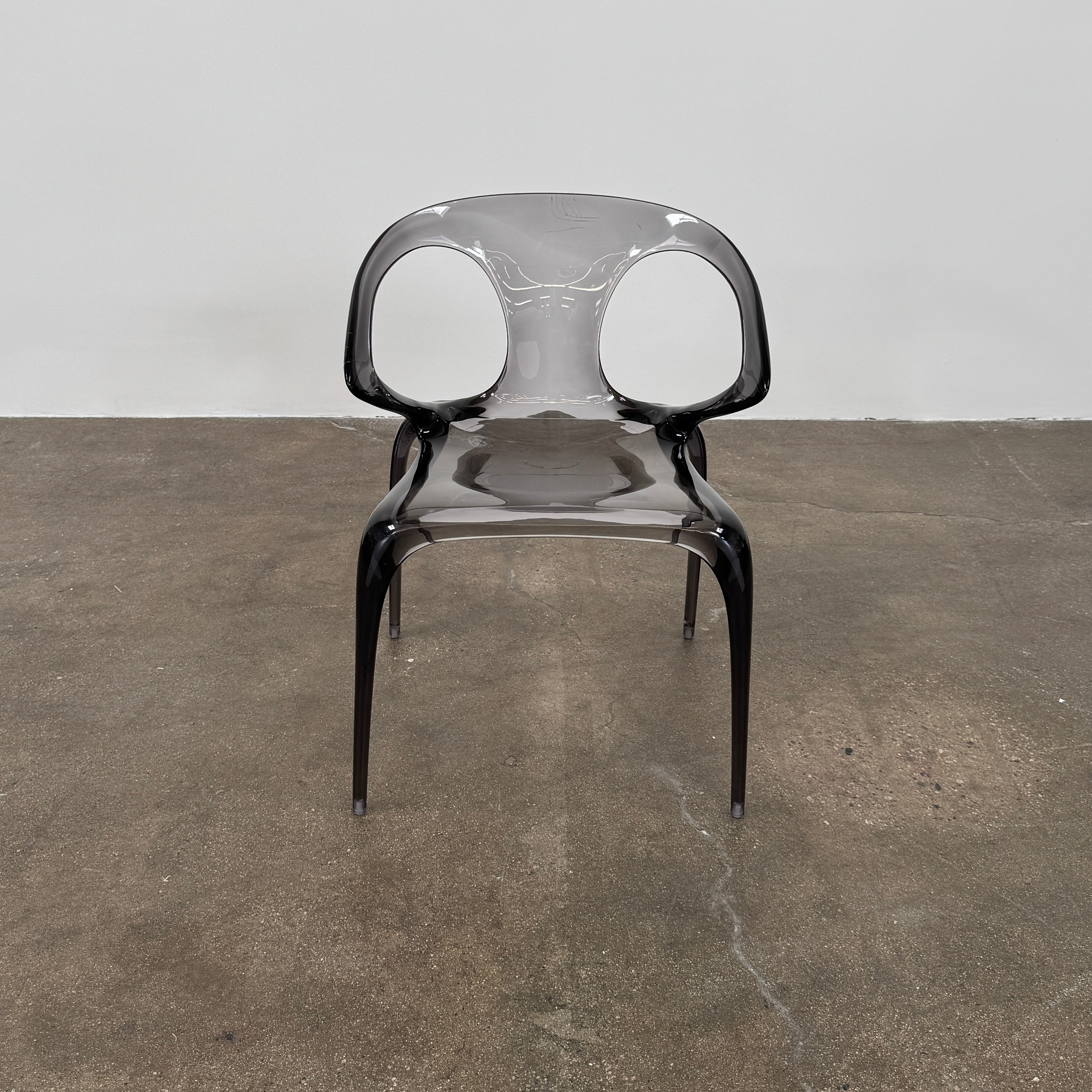 Four stackable Roche Bobois Ava Transparent Chairs (Set of 4) with rounded backs and armrests are arranged in two rows against a plain white background, showcasing the sleek modern style of Roche Bobois.