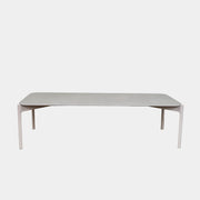 The Dedon Izon Outdoor Coffee Table by Dedon features a flat light gray surface and four slender, angled legs, delivering sleek, weather-resistant style for your outdoor space against a plain white background.