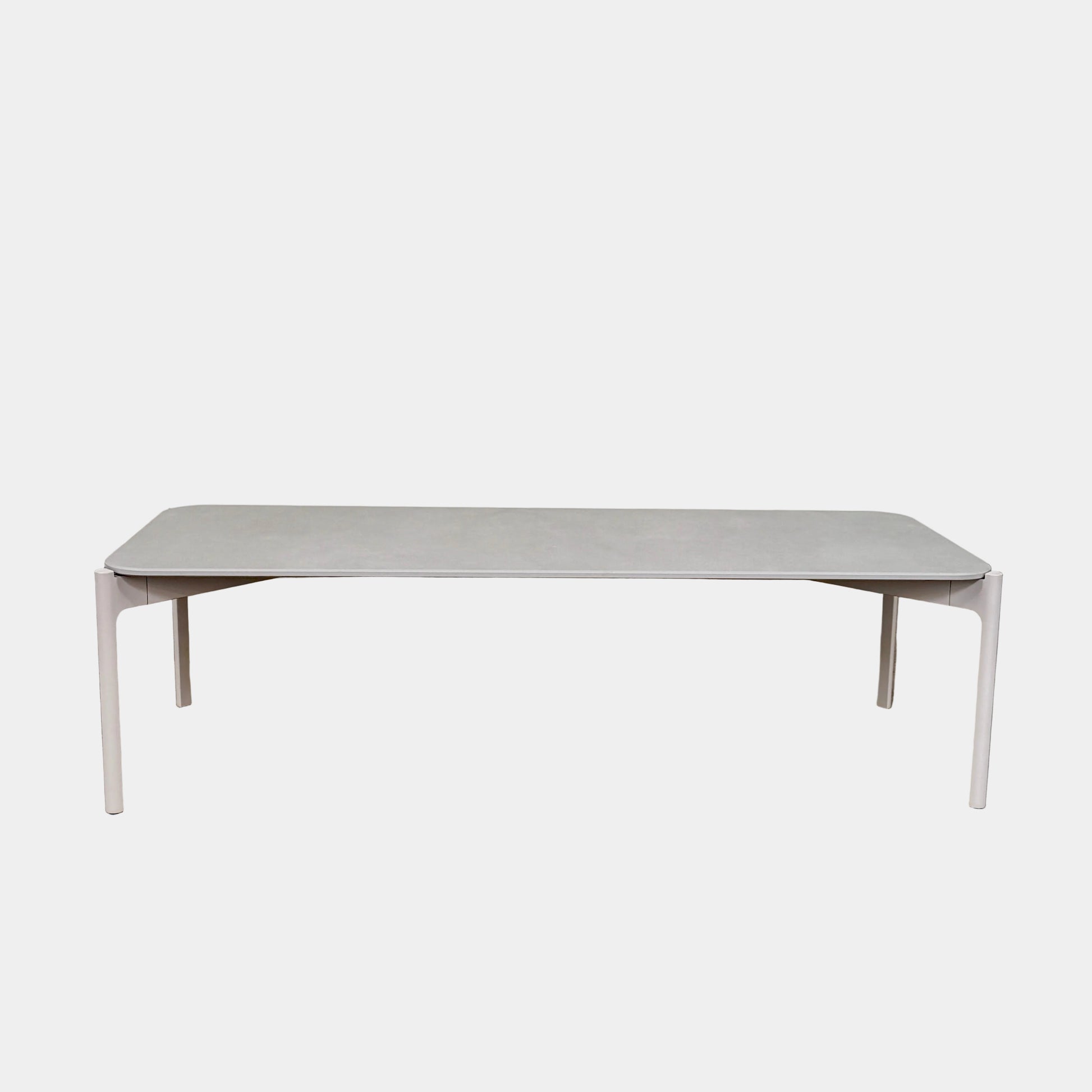 The Dedon Izon Outdoor Coffee Table by Dedon features a flat light gray surface and four slender, angled legs, delivering sleek, weather-resistant style for your outdoor space against a plain white background.