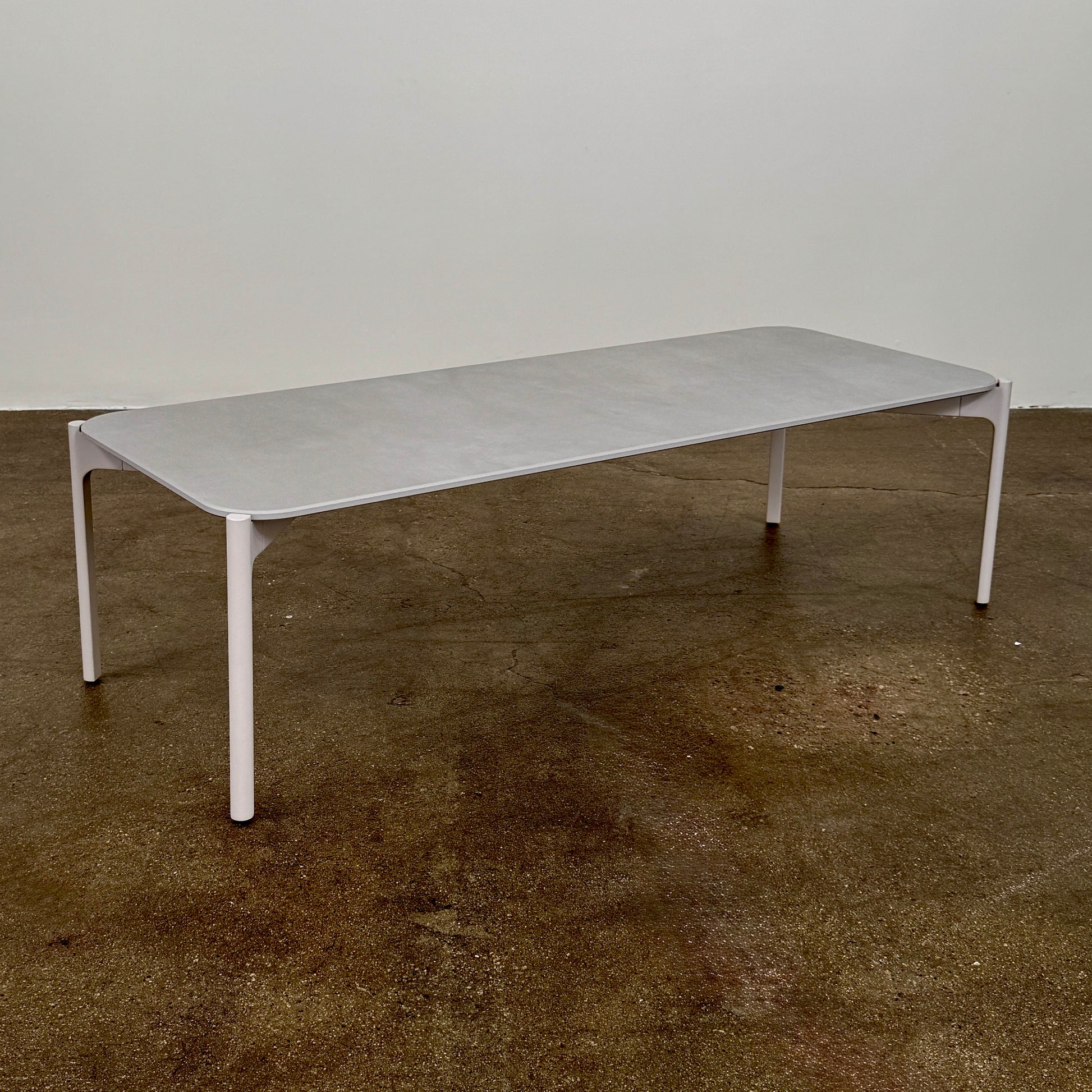 The Dedon Izon Outdoor Coffee Table by Dedon features a flat light gray surface and four slender, angled legs, delivering sleek, weather-resistant style for your outdoor space against a plain white background.