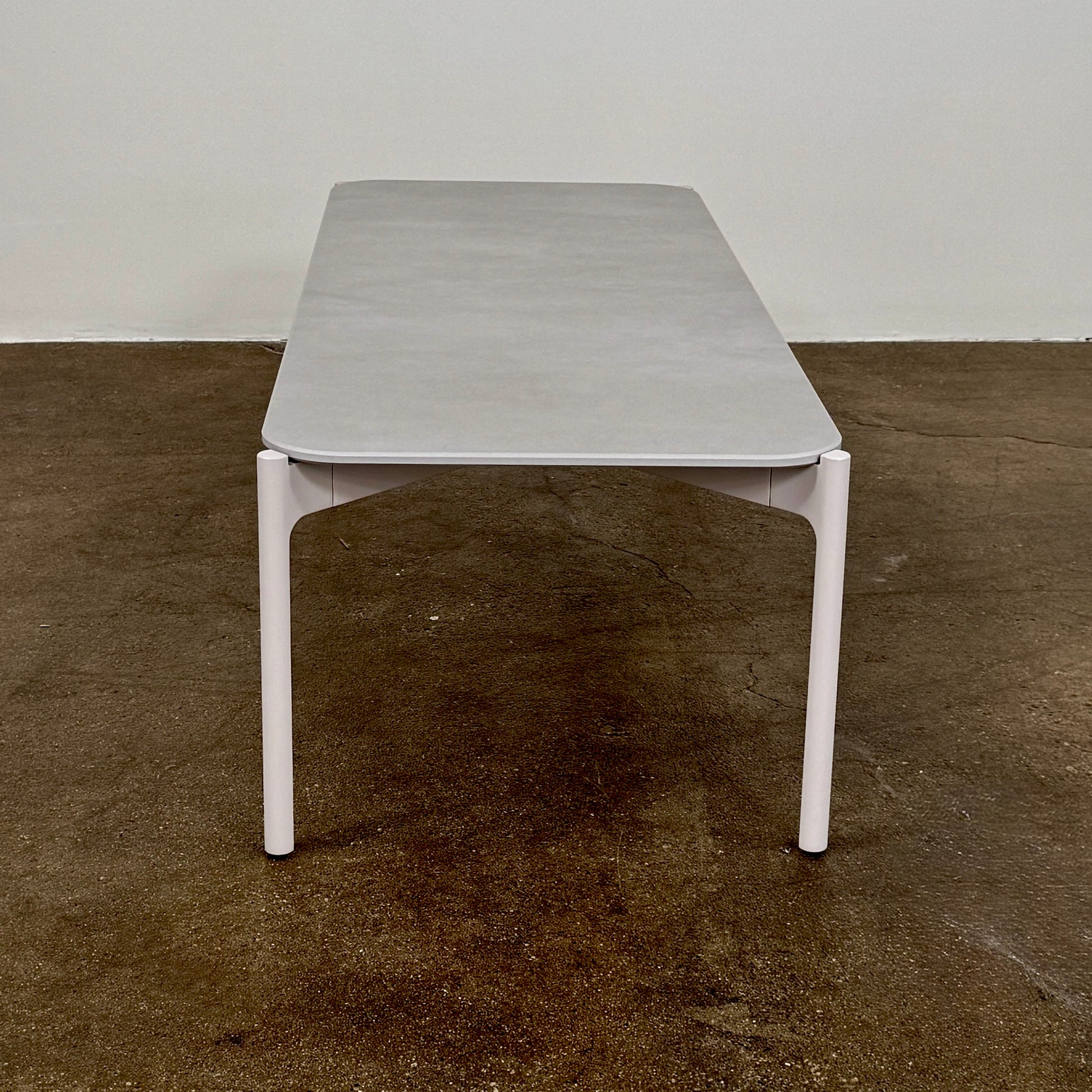 The Dedon Izon Outdoor Coffee Table by Dedon features a flat light gray surface and four slender, angled legs, delivering sleek, weather-resistant style for your outdoor space against a plain white background.
