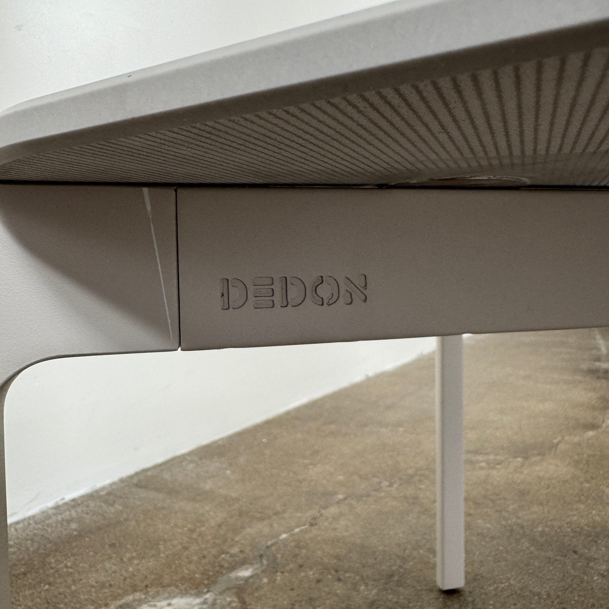 The Dedon Izon Outdoor Coffee Table by Dedon features a flat light gray surface and four slender, angled legs, delivering sleek, weather-resistant style for your outdoor space against a plain white background.