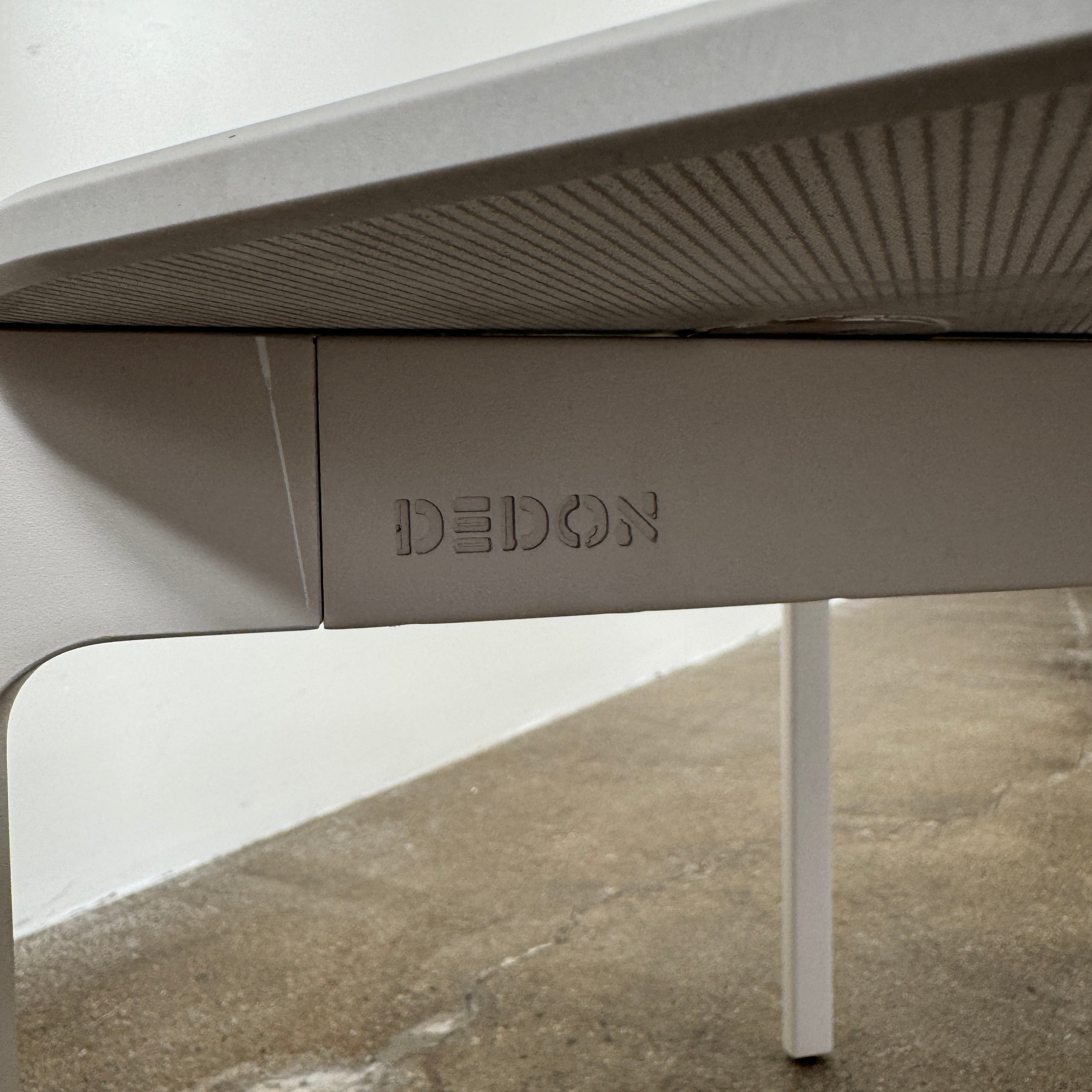 The Dedon Izon Outdoor Coffee Table by Dedon features a flat light gray surface and four slender, angled legs, delivering sleek, weather-resistant style for your outdoor space against a plain white background.