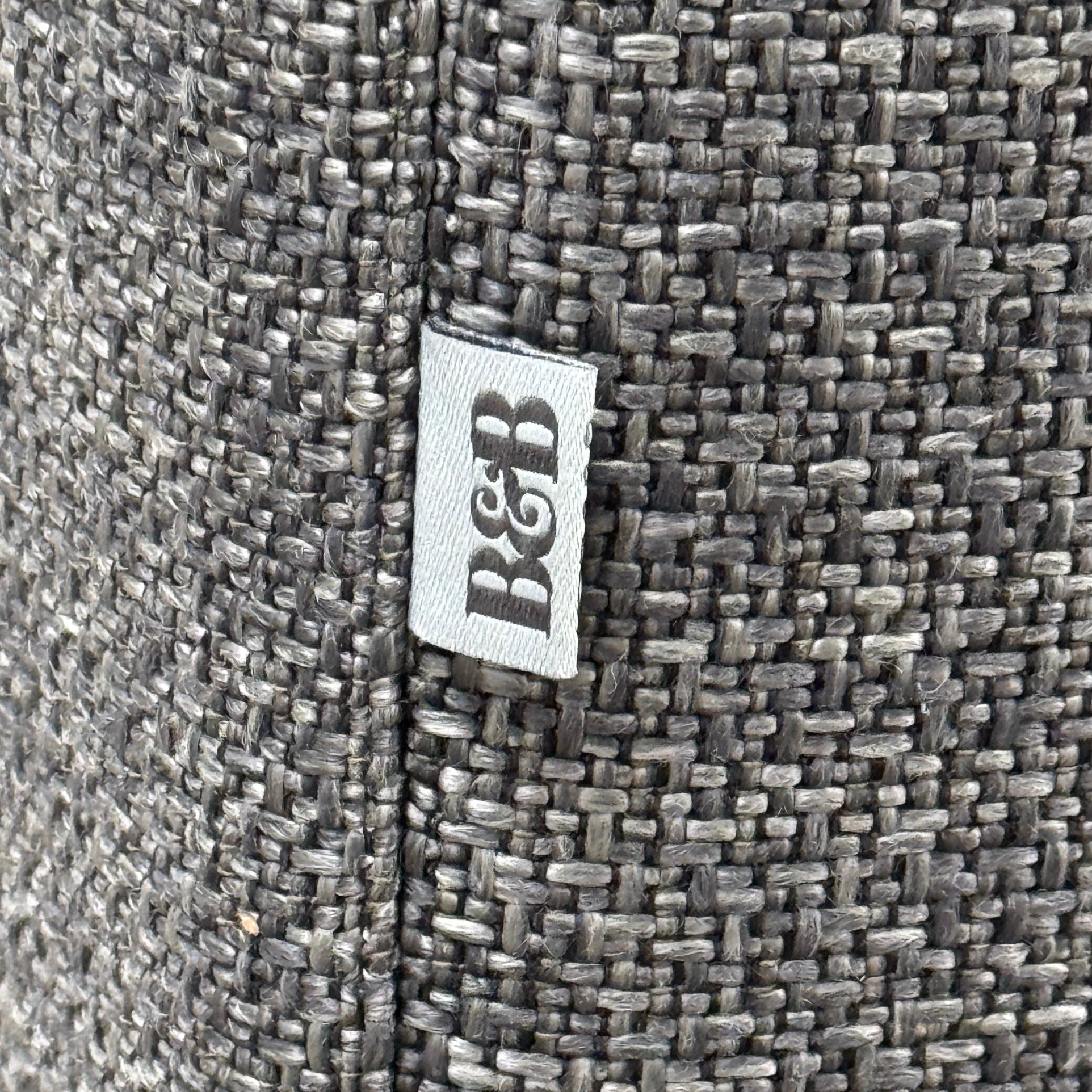 The B&B Italia Michele Club Sectional Sofa by B&B Italia, in dark grey open weave fabric with three seats and a right-side chaise lounge, sits on a concrete floor against a white wall—perfect for modern living spaces.