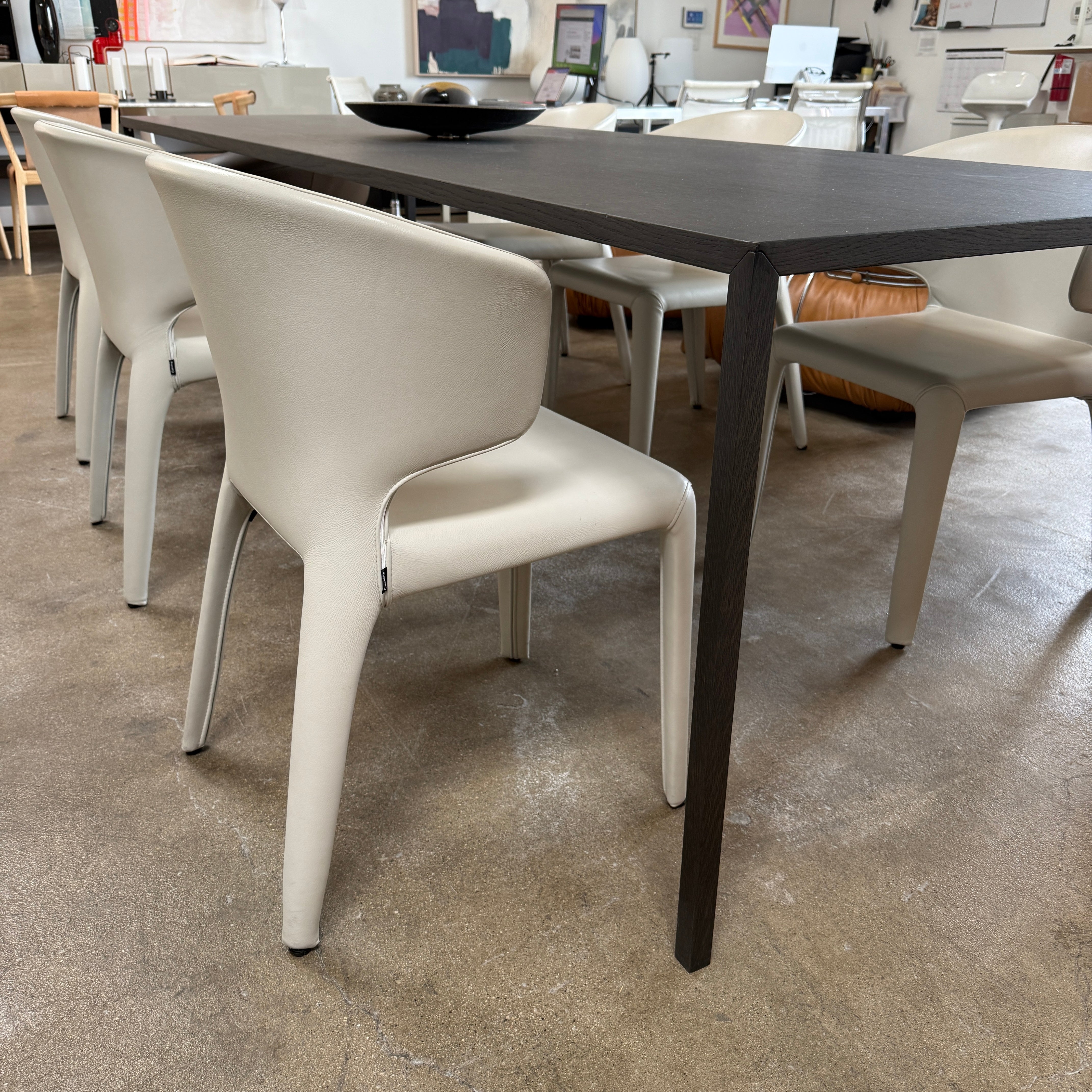 Six Cassina Hola 367 Dining Chairs, identical and upholstered in white leather, are elegantly arranged in two rows on a plain background.