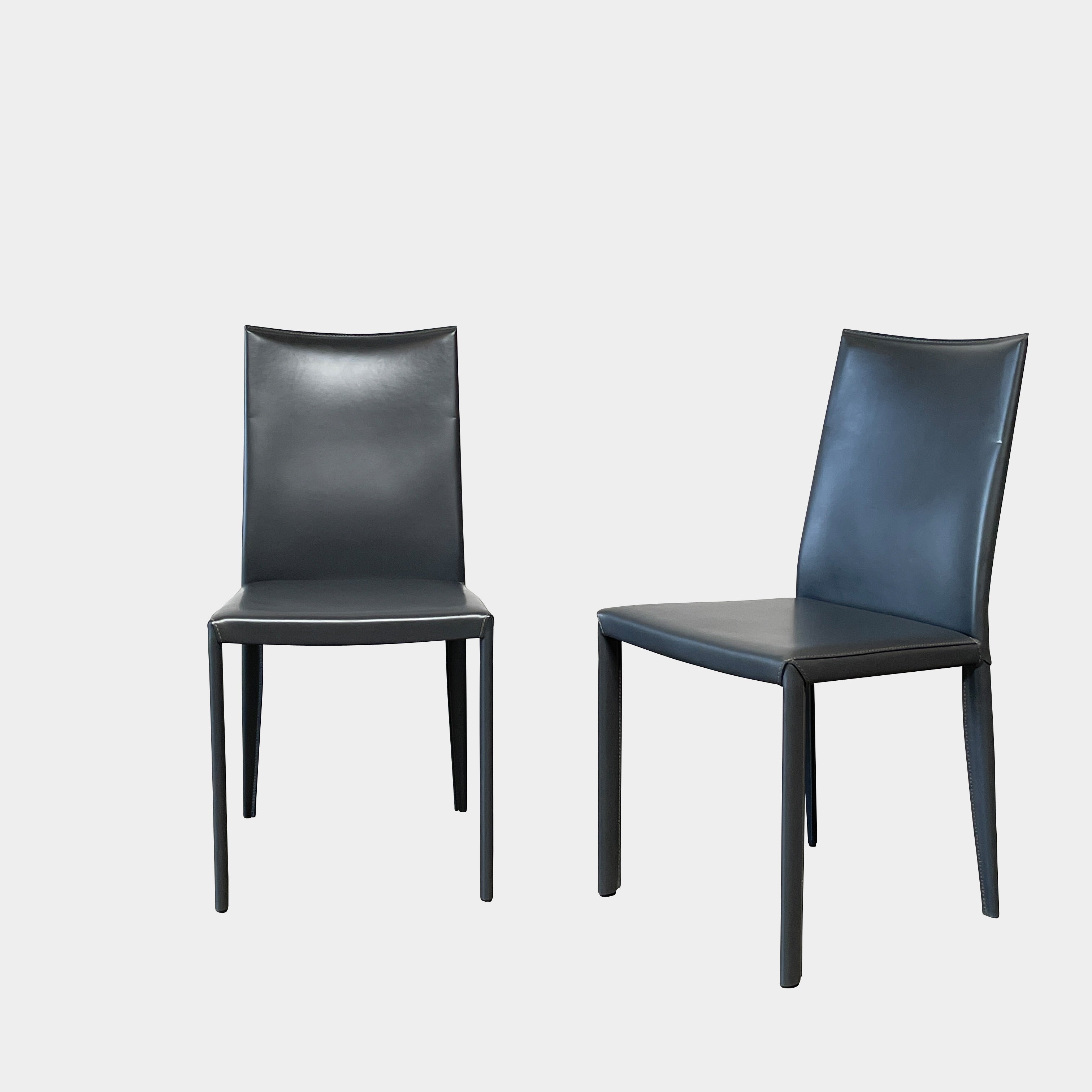 Four Frag Bella Dining Chairs in Dark Grey Leather with metal legs, arranged in a straight line against a plain white background.