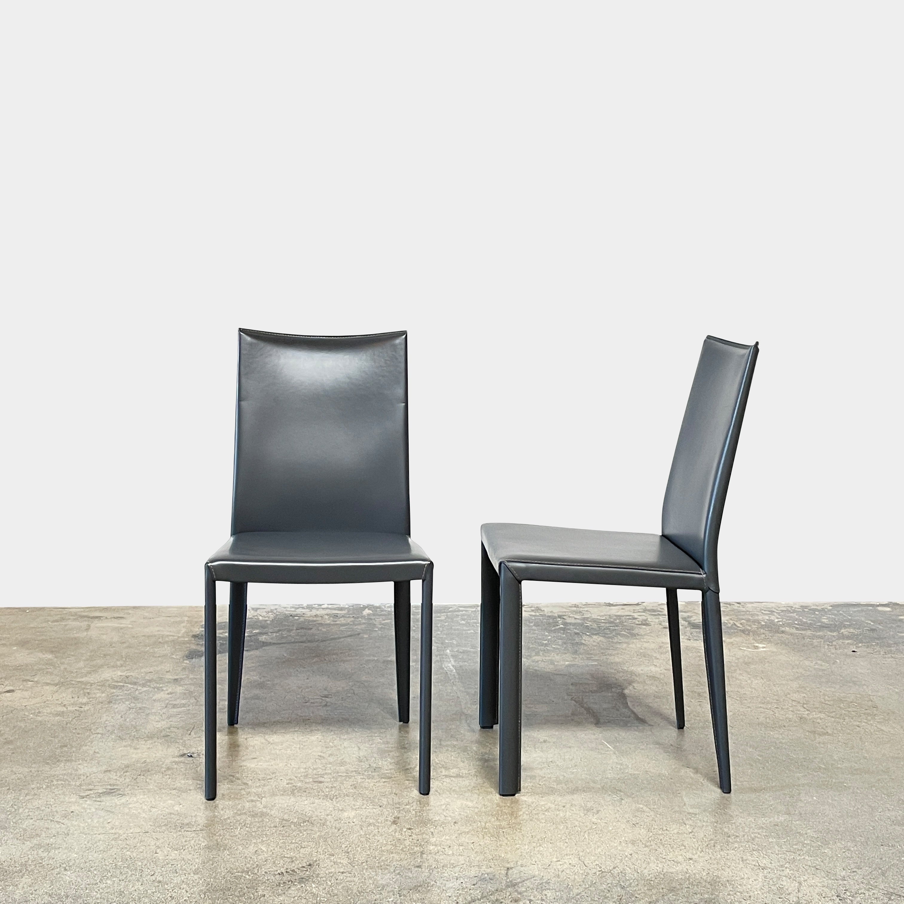 Four Frag Bella Dining Chairs in Dark Grey Leather with metal legs, arranged in a straight line against a plain white background.