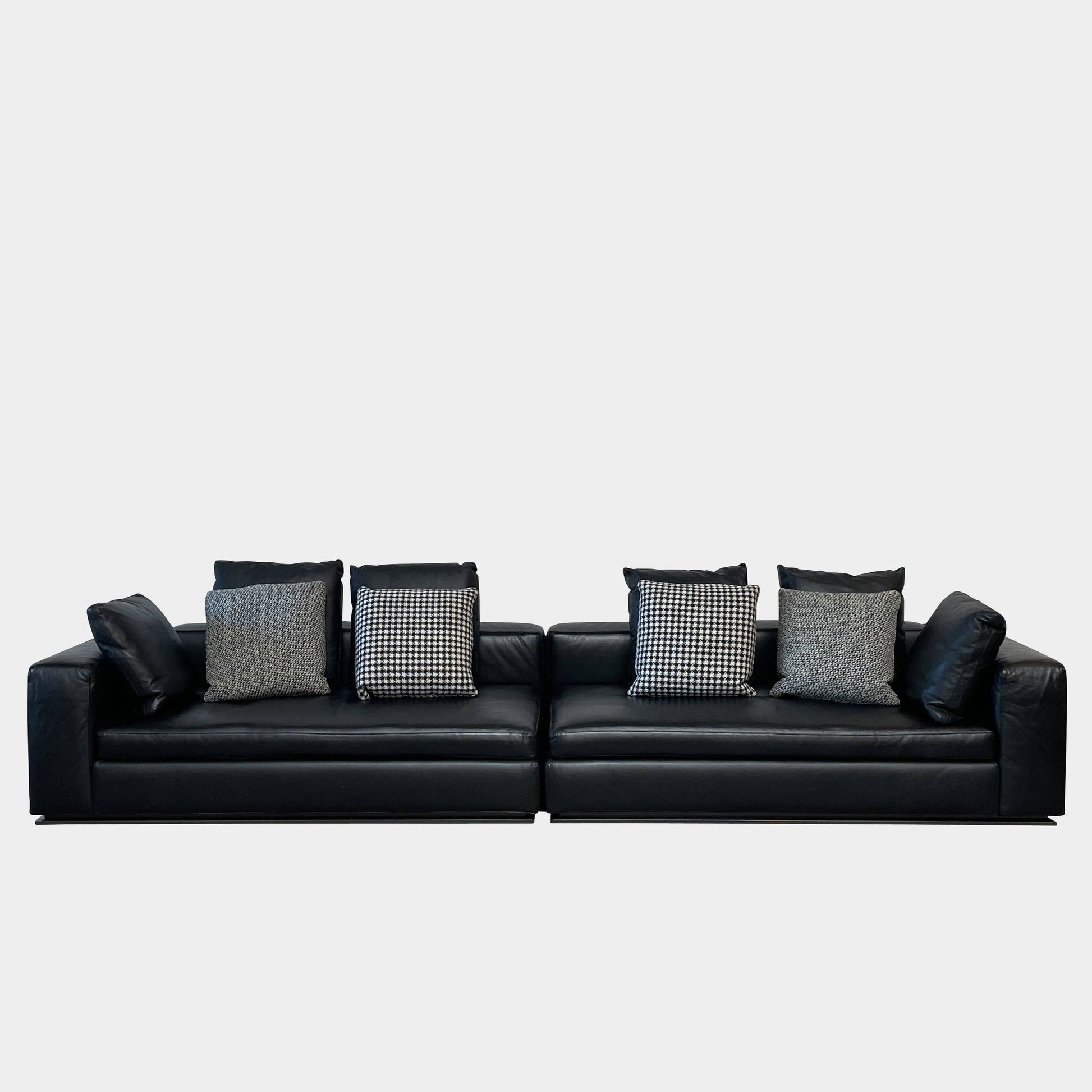 A Minotti Hamilton Black Leather Sofa with multiple cushions, designed by Rodolfo Dordoni, isolated on a white background.