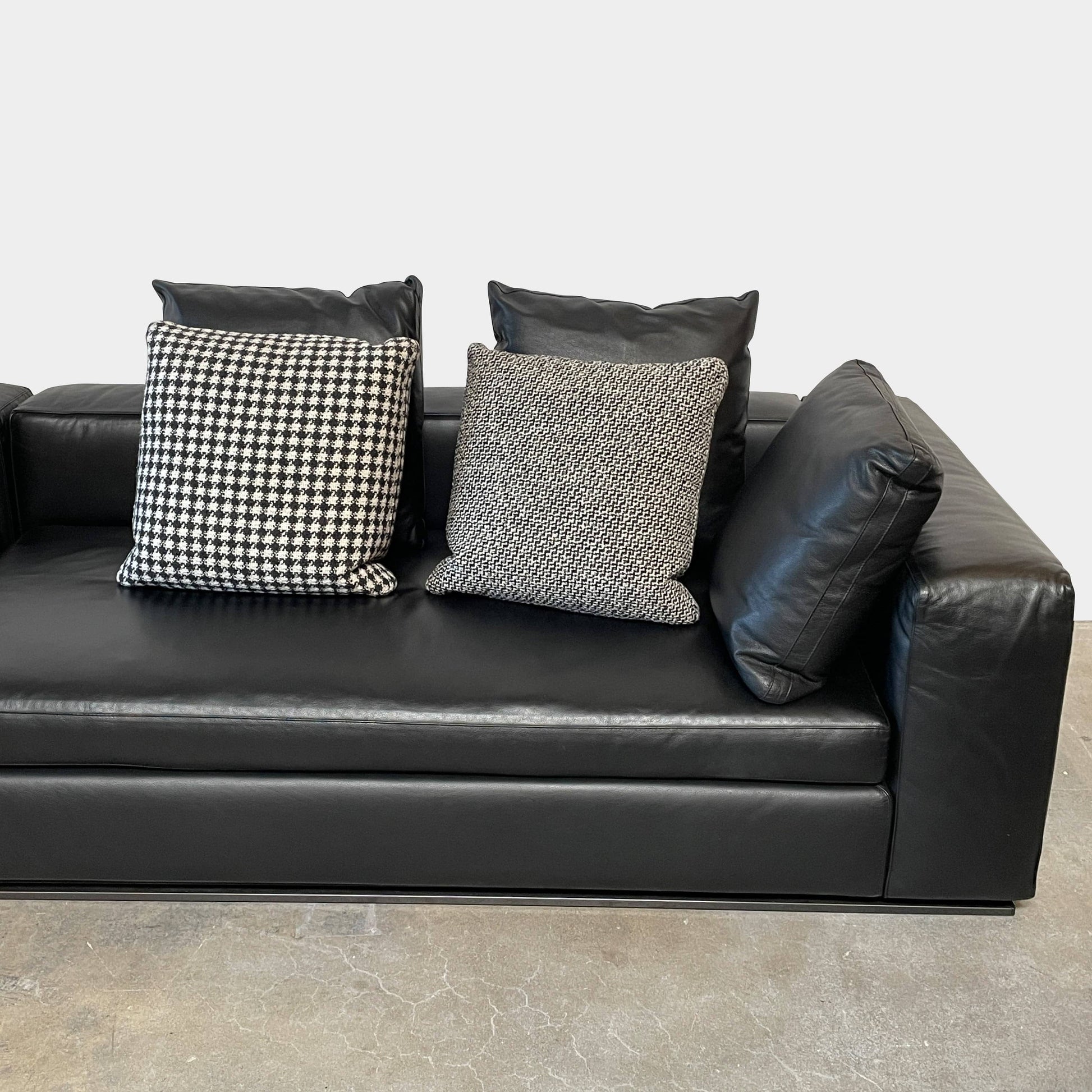 A Minotti Hamilton Black Leather Sofa with multiple cushions, designed by Rodolfo Dordoni, isolated on a white background.