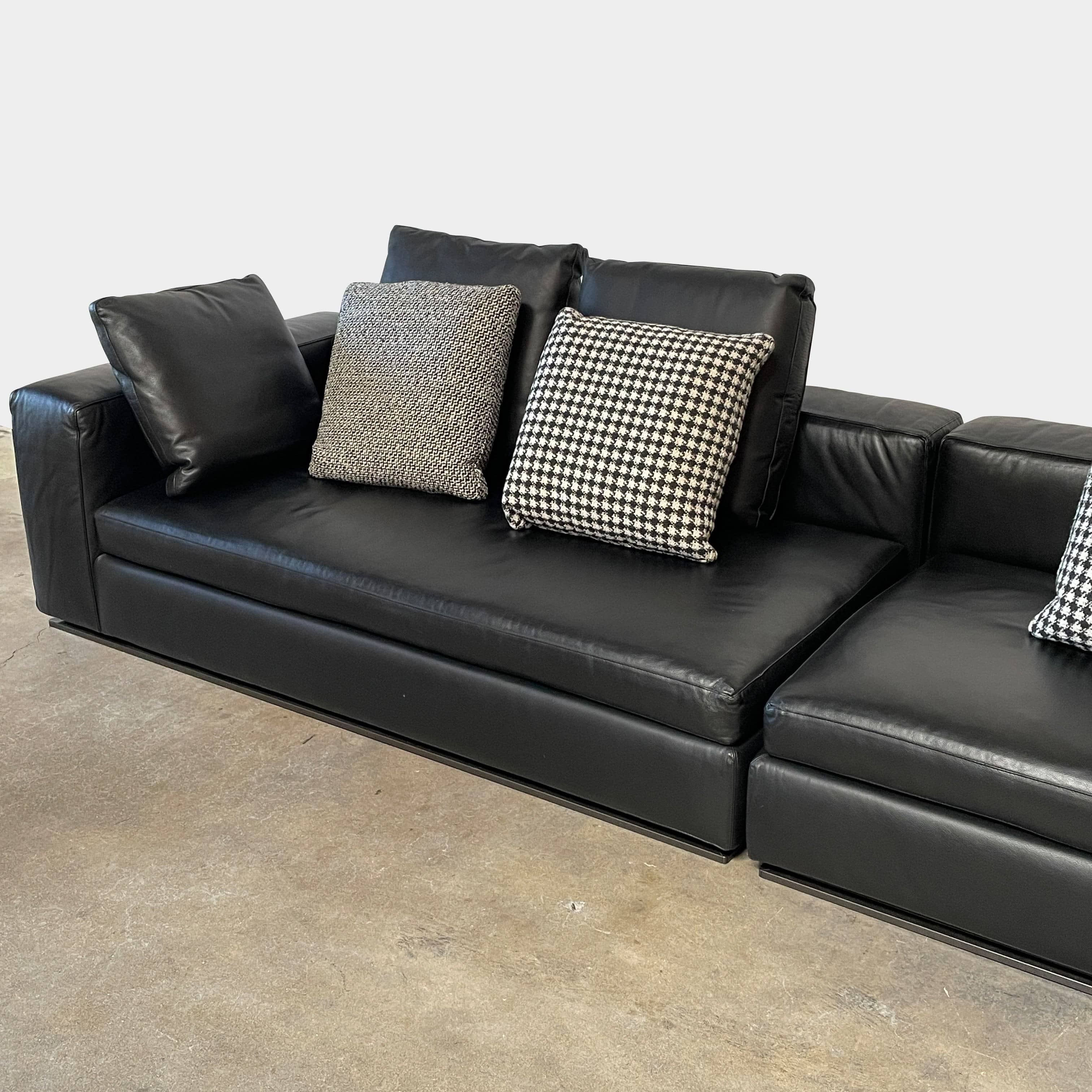 A Minotti Hamilton Black Leather Sofa with multiple cushions, designed by Rodolfo Dordoni, isolated on a white background.