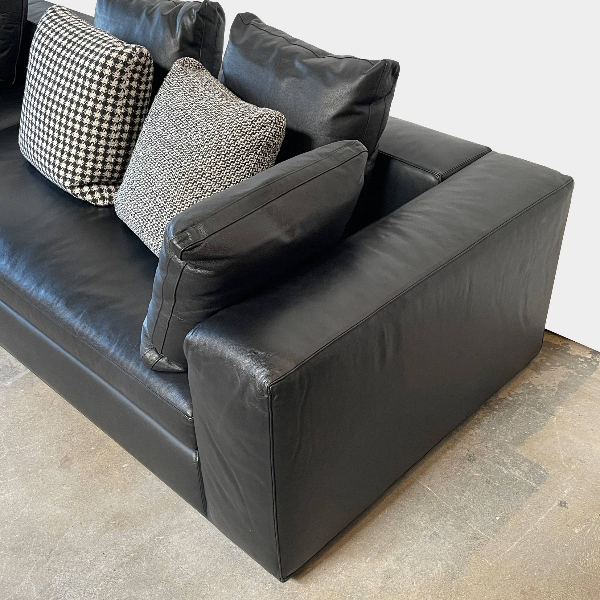 A Minotti Hamilton Black Leather Sofa with multiple cushions, designed by Rodolfo Dordoni, isolated on a white background.