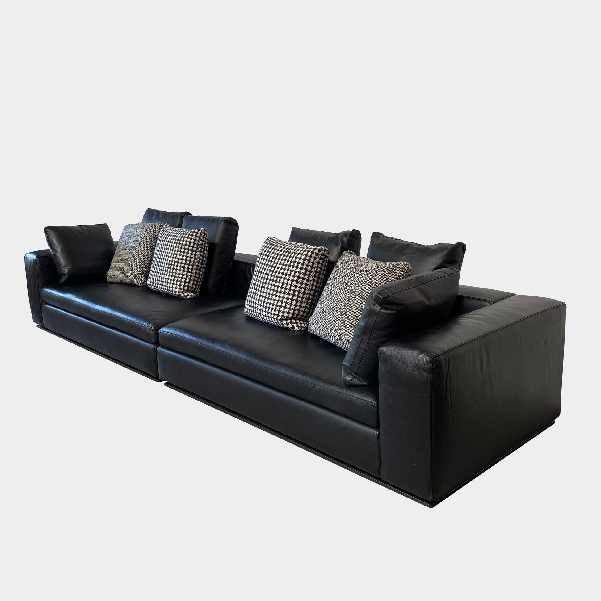 A Minotti Hamilton Black Leather Sofa with multiple cushions, designed by Rodolfo Dordoni, isolated on a white background.