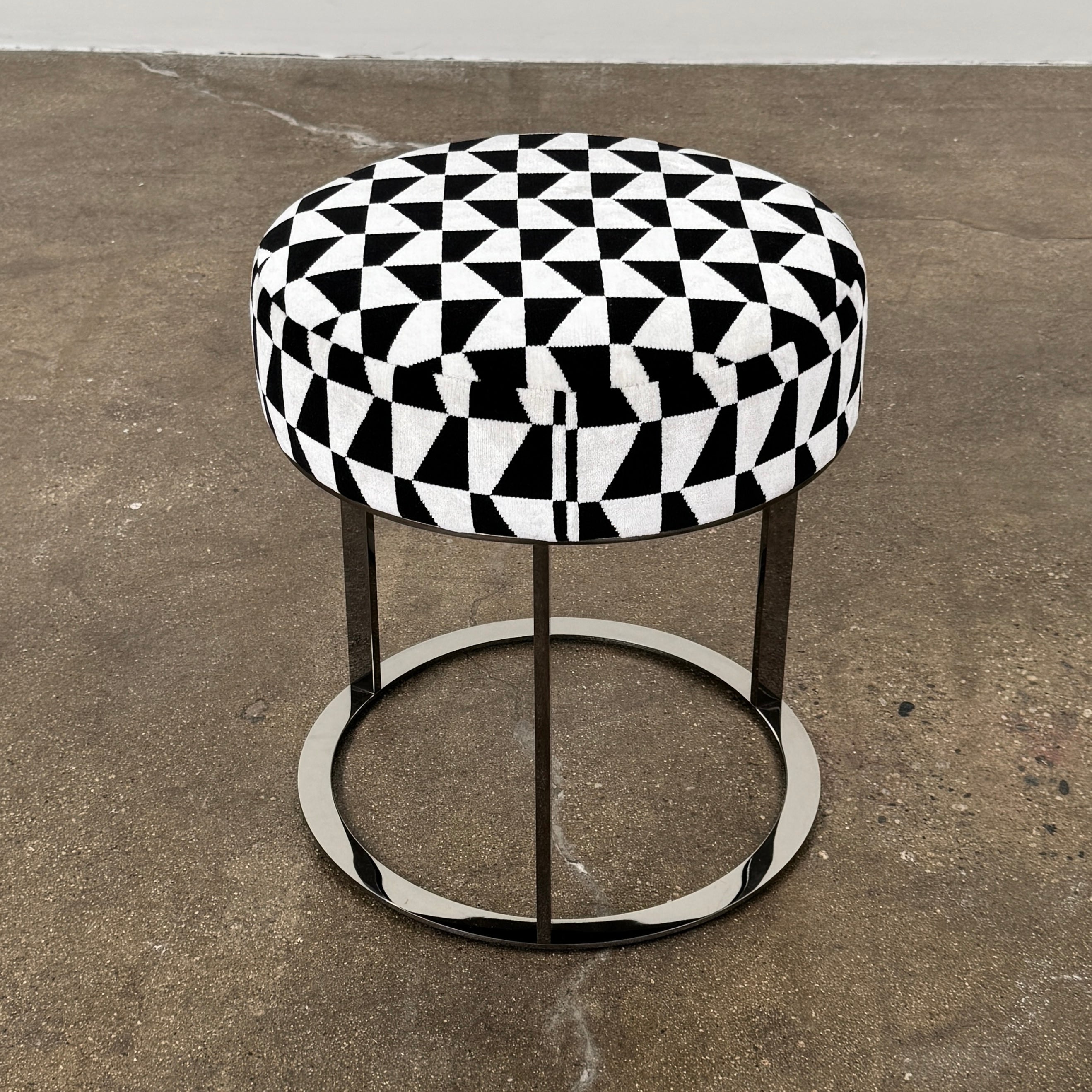 The B&B Italia Frank Ottoman features a black and white geometric cushion on a metal base with three vertical supports and a circular footrest.