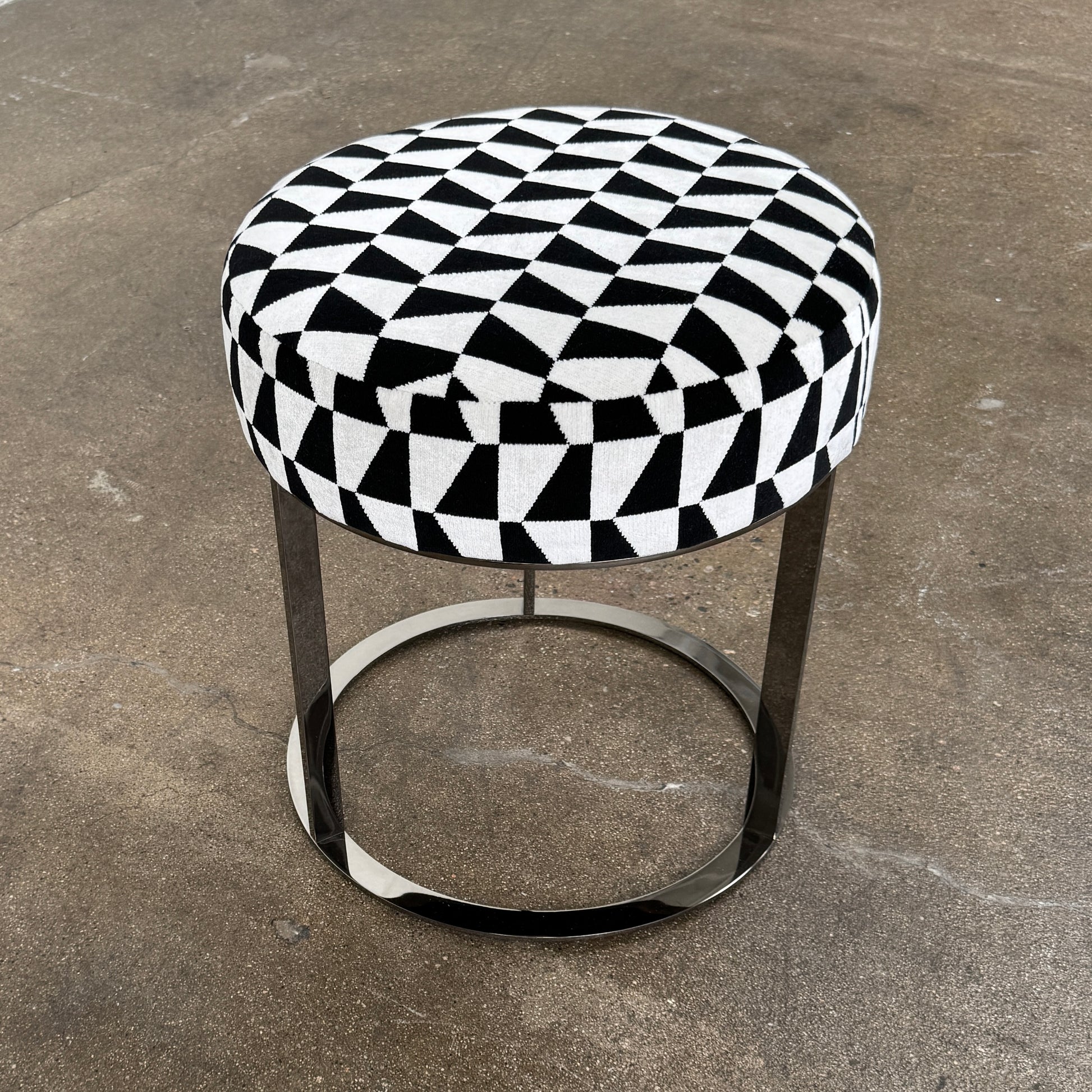 The B&B Italia Frank Ottoman features a black and white geometric cushion on a metal base with three vertical supports and a circular footrest.