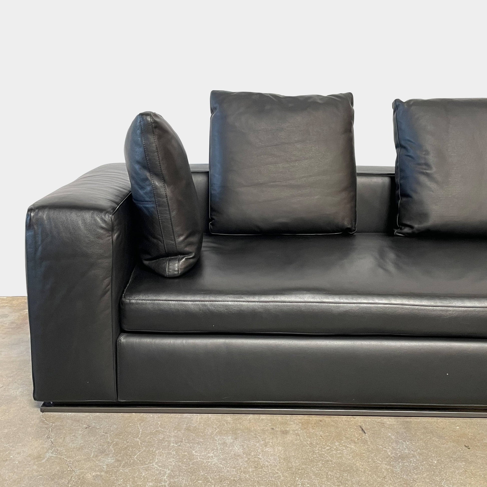 A Minotti Hamilton Black Leather Sofa with multiple cushions, designed by Rodolfo Dordoni, isolated on a white background.