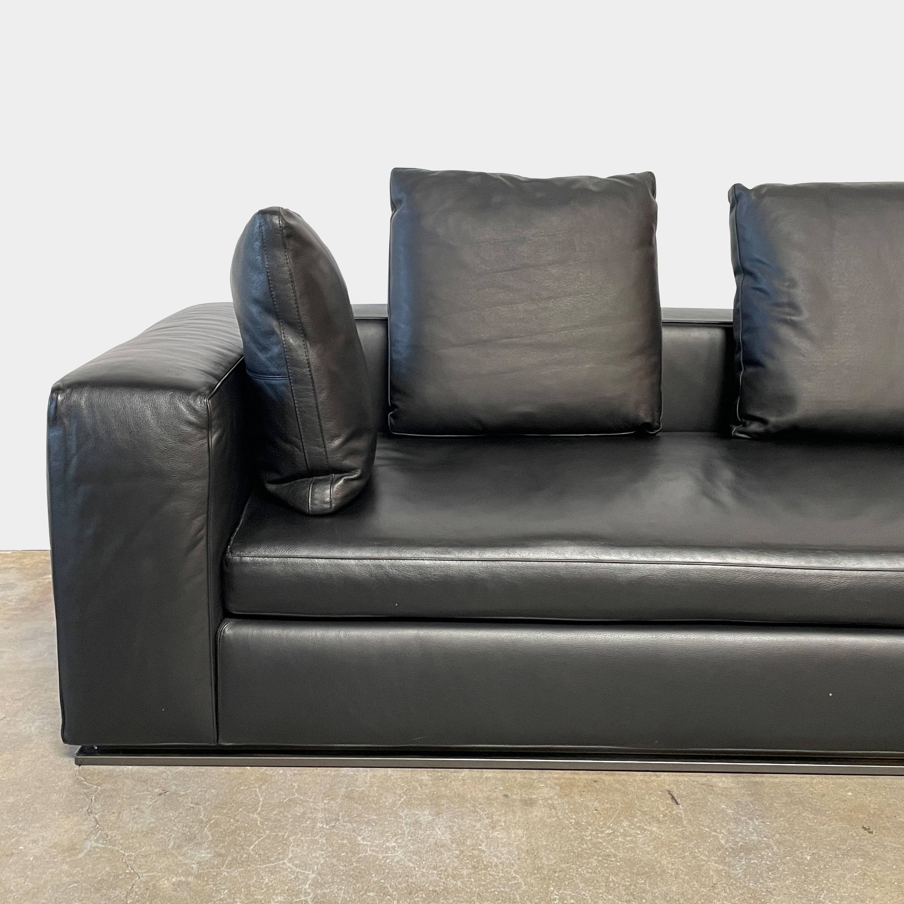A Minotti Hamilton Black Leather Sofa with multiple cushions, designed by Rodolfo Dordoni, isolated on a white background.