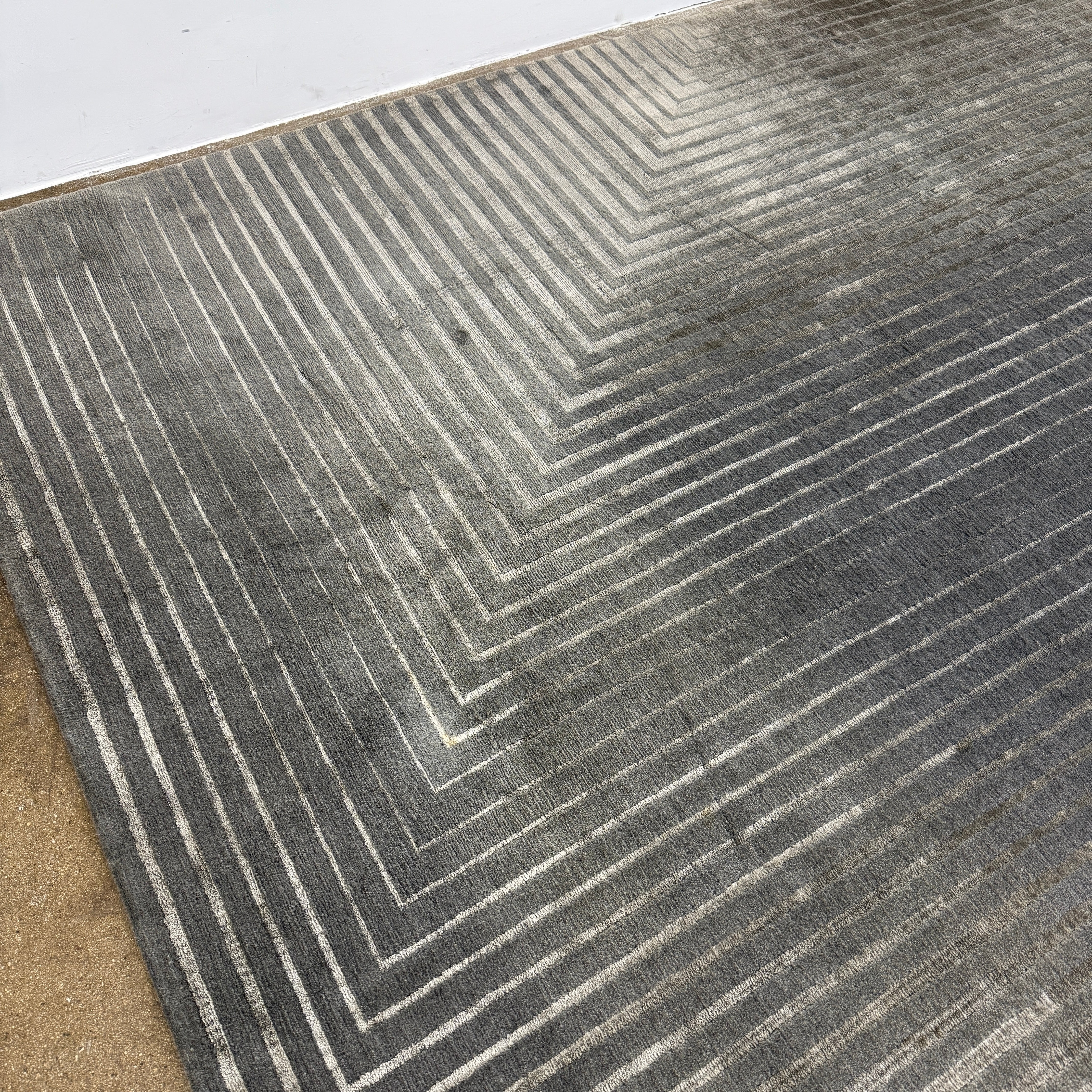 The Delinear Detour Rug 8 x 10 by Delinear features a contemporary rectangular design with a gradient gray pattern and angular geometric lines arranged in a stepped motif.