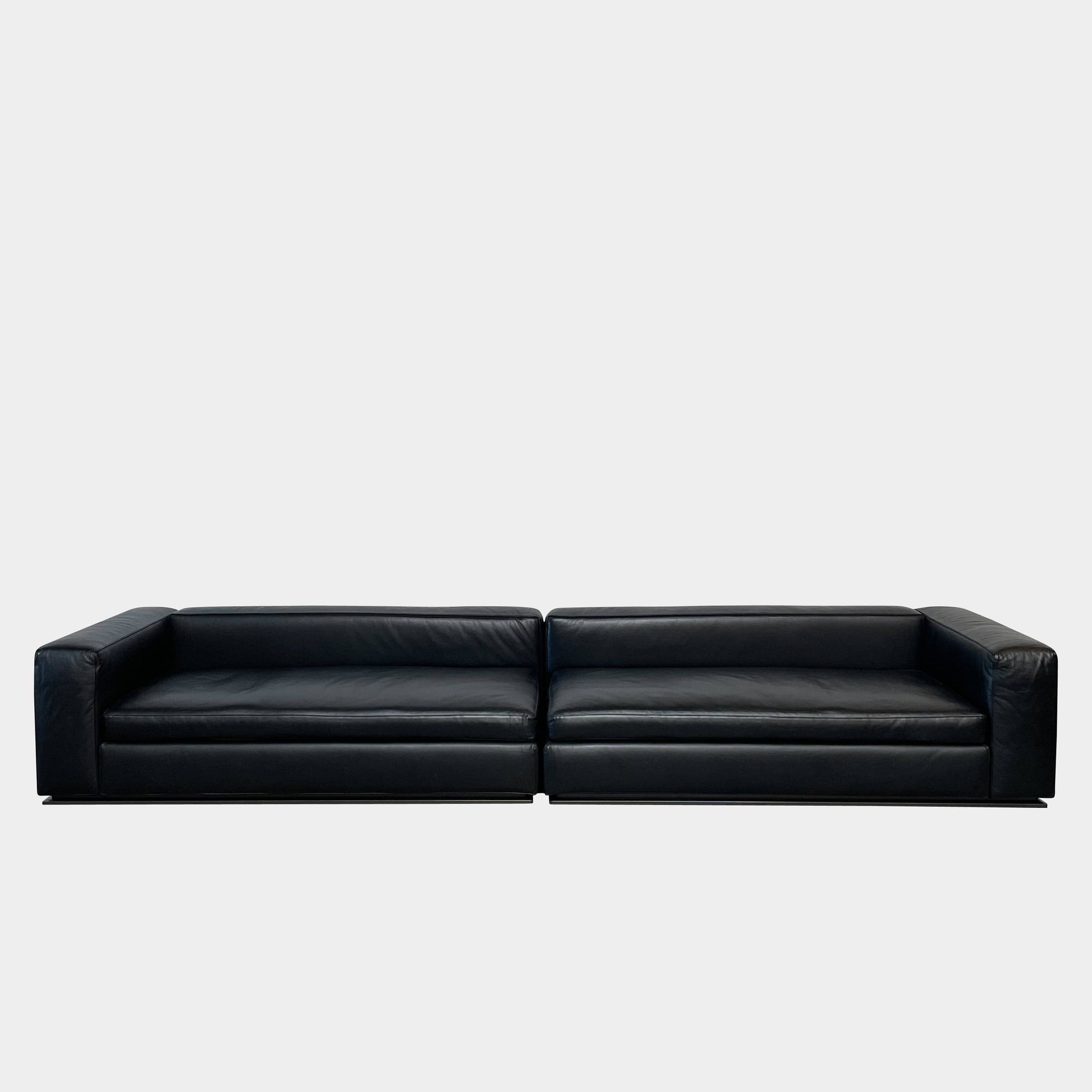A Minotti Hamilton Black Leather Sofa with multiple cushions, designed by Rodolfo Dordoni, isolated on a white background.