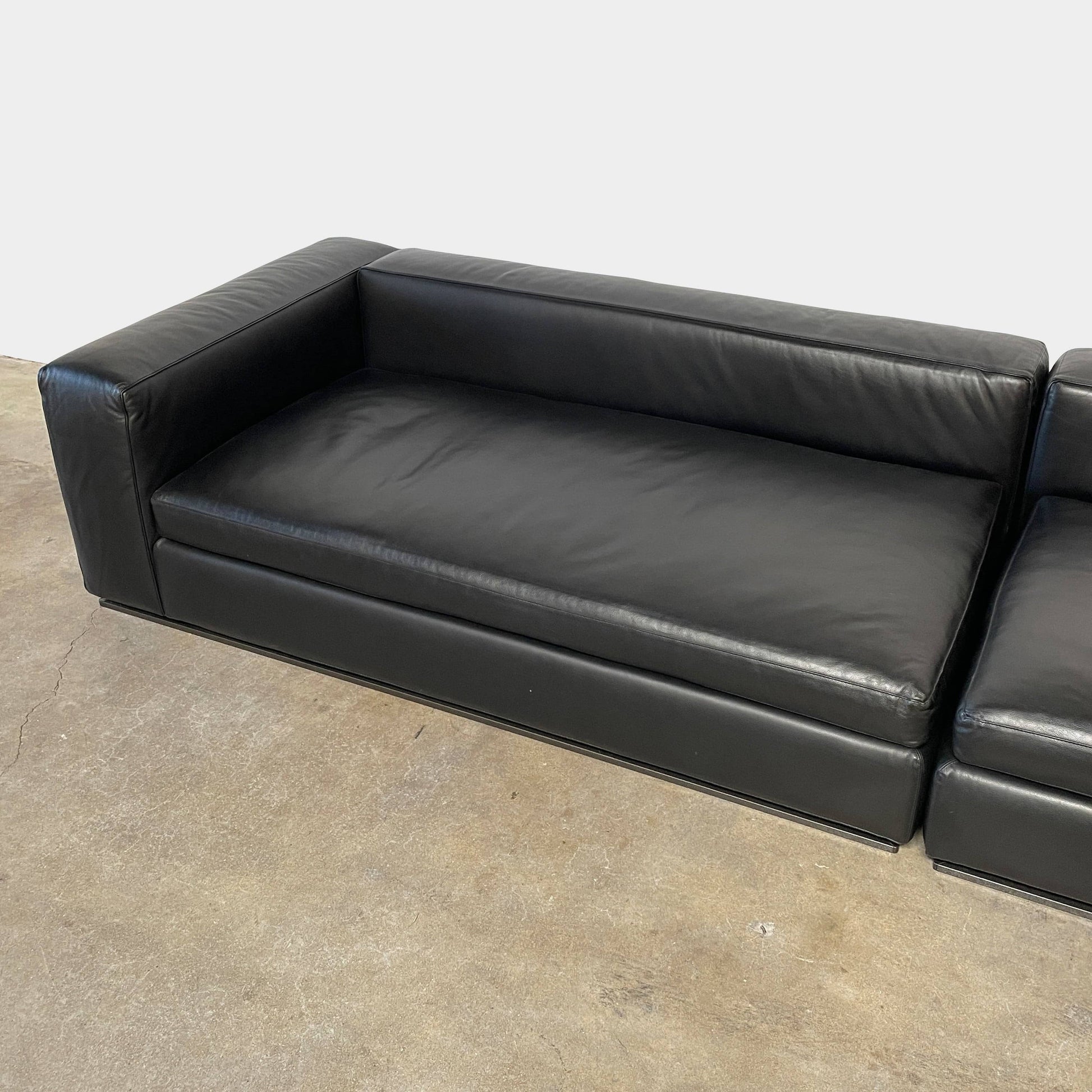 A Minotti Hamilton Black Leather Sofa with multiple cushions, designed by Rodolfo Dordoni, isolated on a white background.