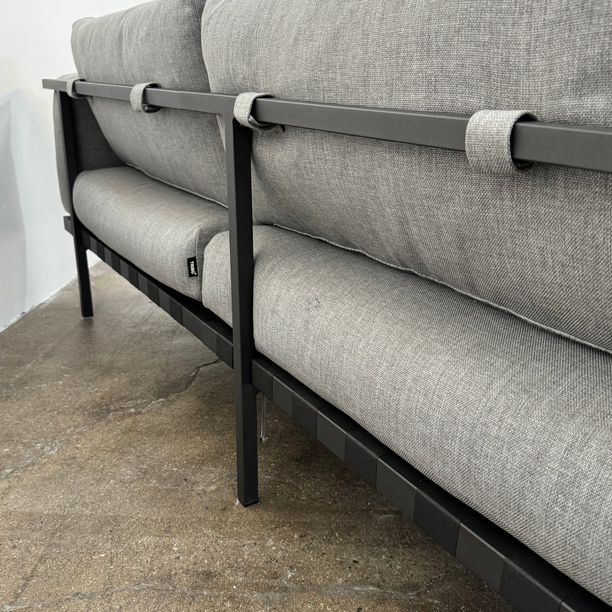 The Tribu Natal Alu Outdoor Sectional Sofa by Tribú features light gray cushions, five dark gray throw pillows, and a sleek black aluminum frame—perfect for adding modern style to your patio.