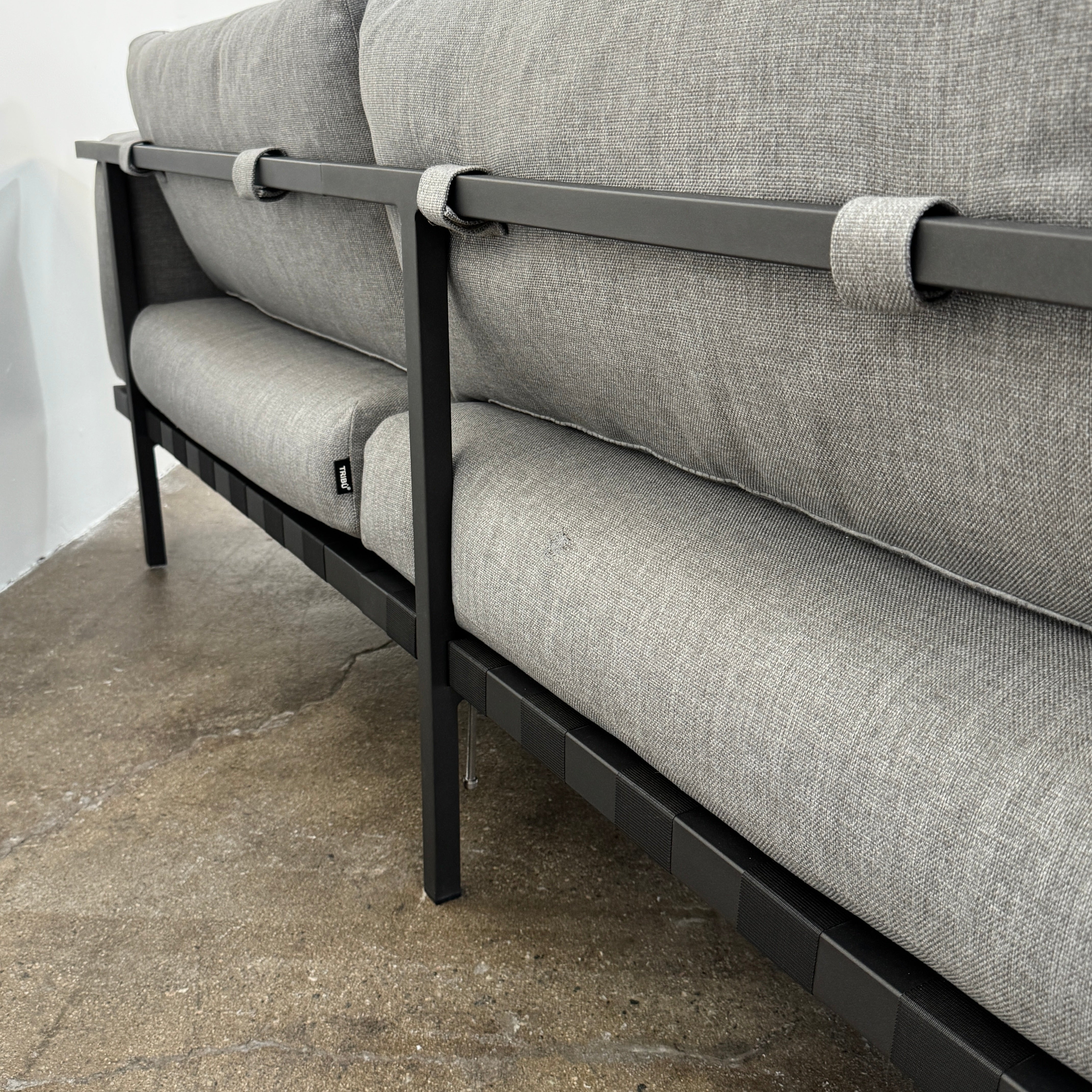The Tribu Natal Alu Outdoor Sectional Sofa by Tribú features light gray cushions, five dark gray throw pillows, and a sleek black aluminum frame—perfect for adding modern style to your patio.