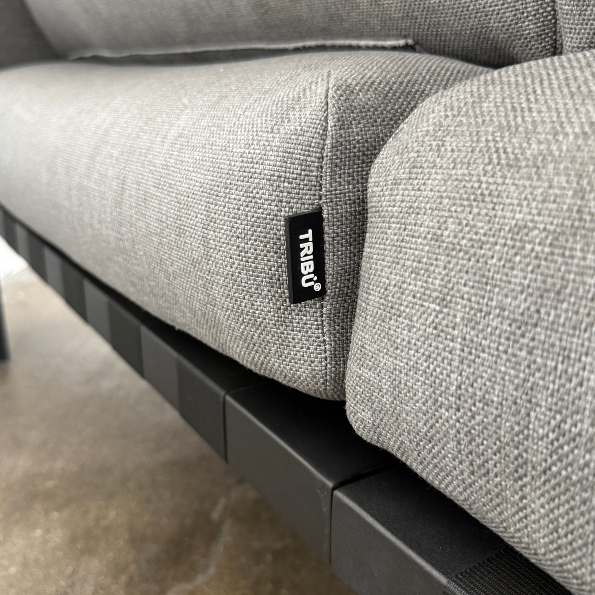 The Tribu Natal Alu Outdoor Sectional Sofa by Tribú features light gray cushions, five dark gray throw pillows, and a sleek black aluminum frame—perfect for adding modern style to your patio.