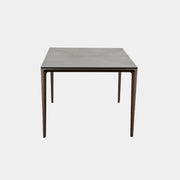The Rimadesio Long Island Table by Rimadesio features a square black oak top with a dark wood finish, four slender legs, and modern Italian design, displayed against a plain white background.