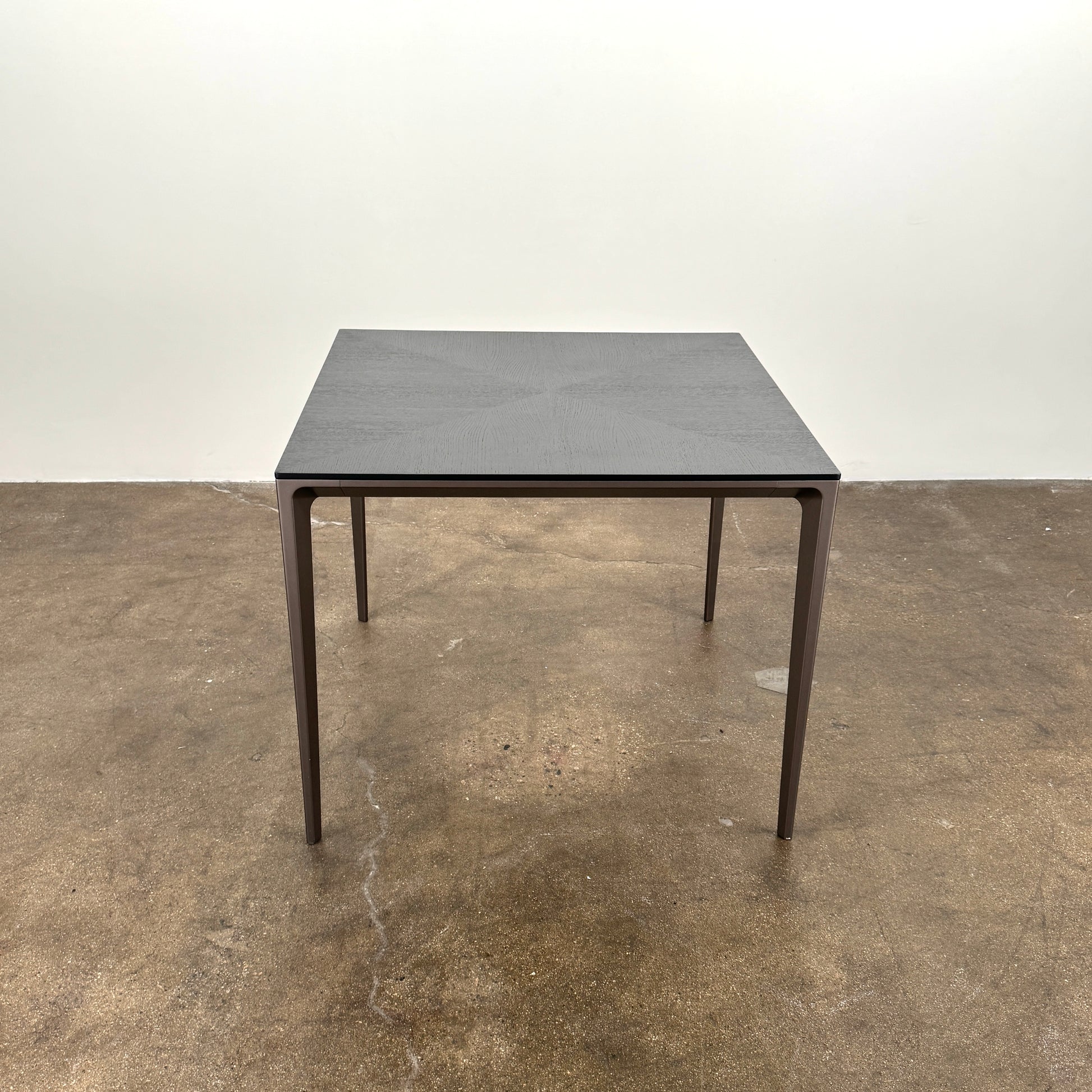 The Rimadesio Long Island Table by Rimadesio features a square black oak top with a dark wood finish, four slender legs, and modern Italian design, displayed against a plain white background.
