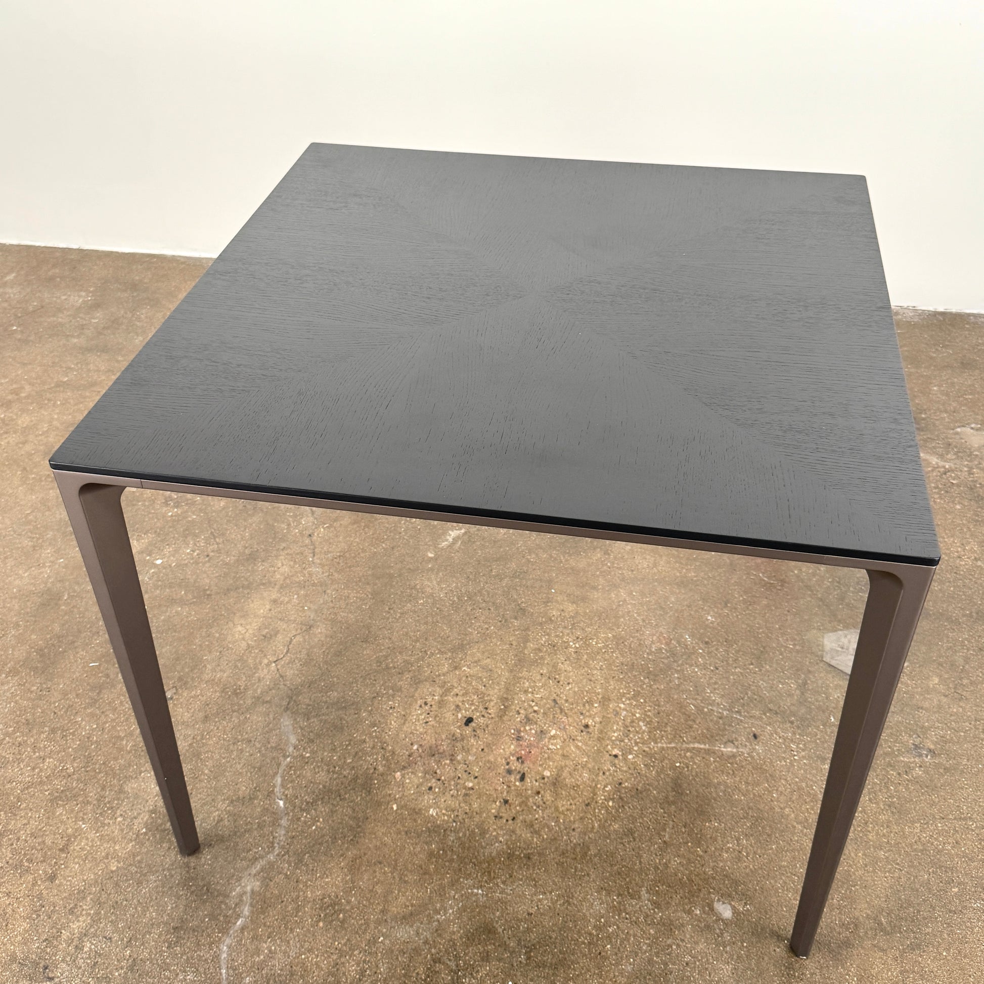 The Rimadesio Long Island Table by Rimadesio features a square black oak top with a dark wood finish, four slender legs, and modern Italian design, displayed against a plain white background.