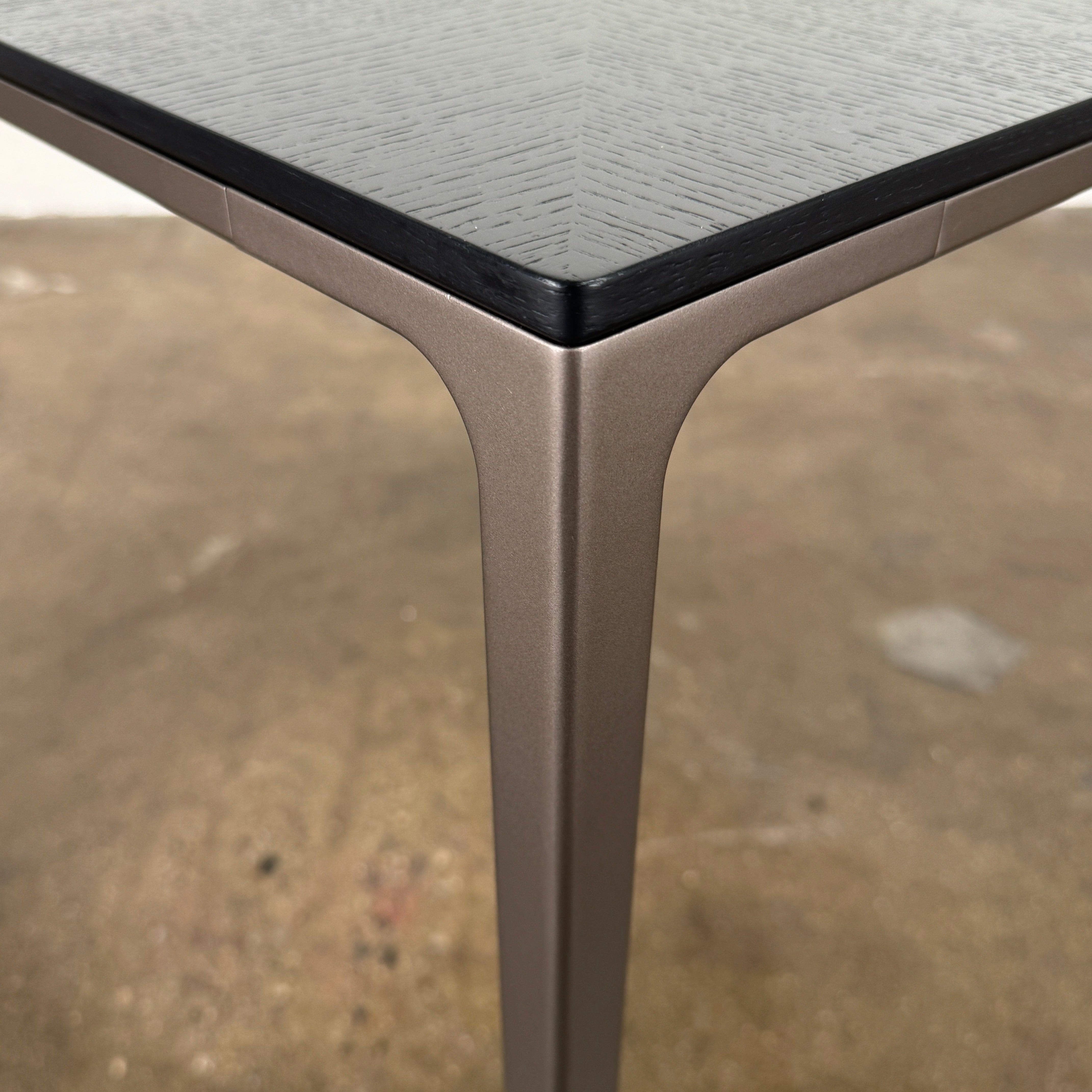 The Rimadesio Long Island Table by Rimadesio features a square black oak top with a dark wood finish, four slender legs, and modern Italian design, displayed against a plain white background.