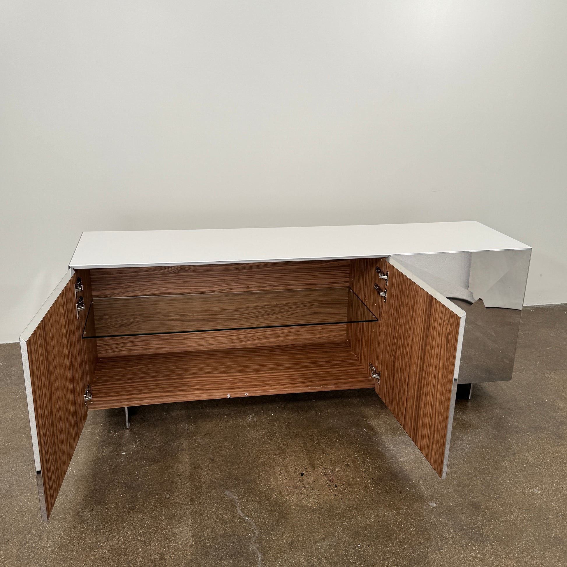 The Riflessi Cubric Sideboard by Riflessi features three mirrored doors and a geometric jagged top edge, shown here against a plain white wall on a concrete floor.