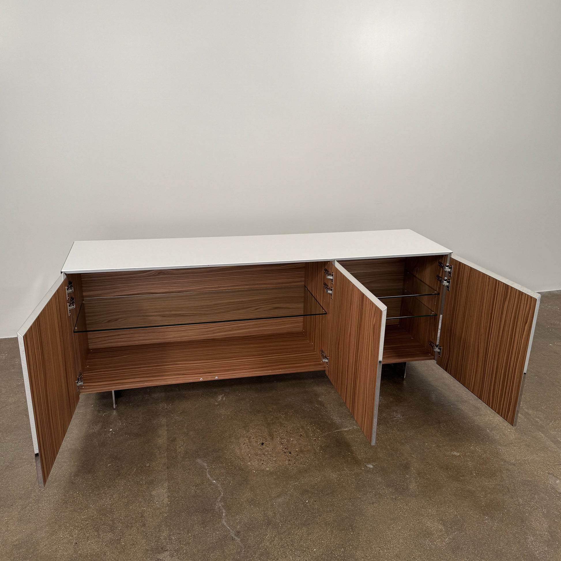 The Riflessi Cubric Sideboard by Riflessi features three mirrored doors and a geometric jagged top edge, shown here against a plain white wall on a concrete floor.