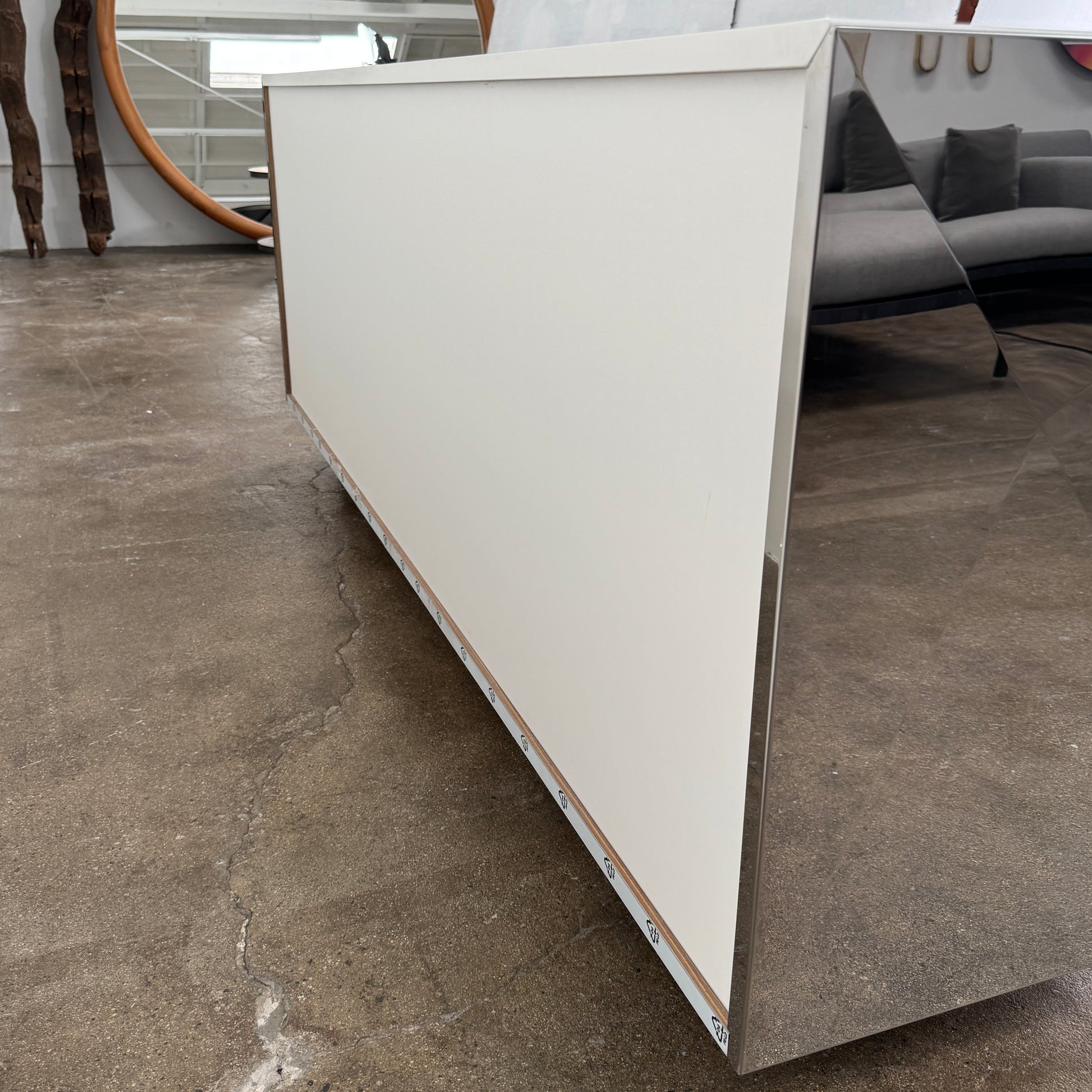The Riflessi Cubric Sideboard by Riflessi features three mirrored doors and a geometric jagged top edge, shown here against a plain white wall on a concrete floor.