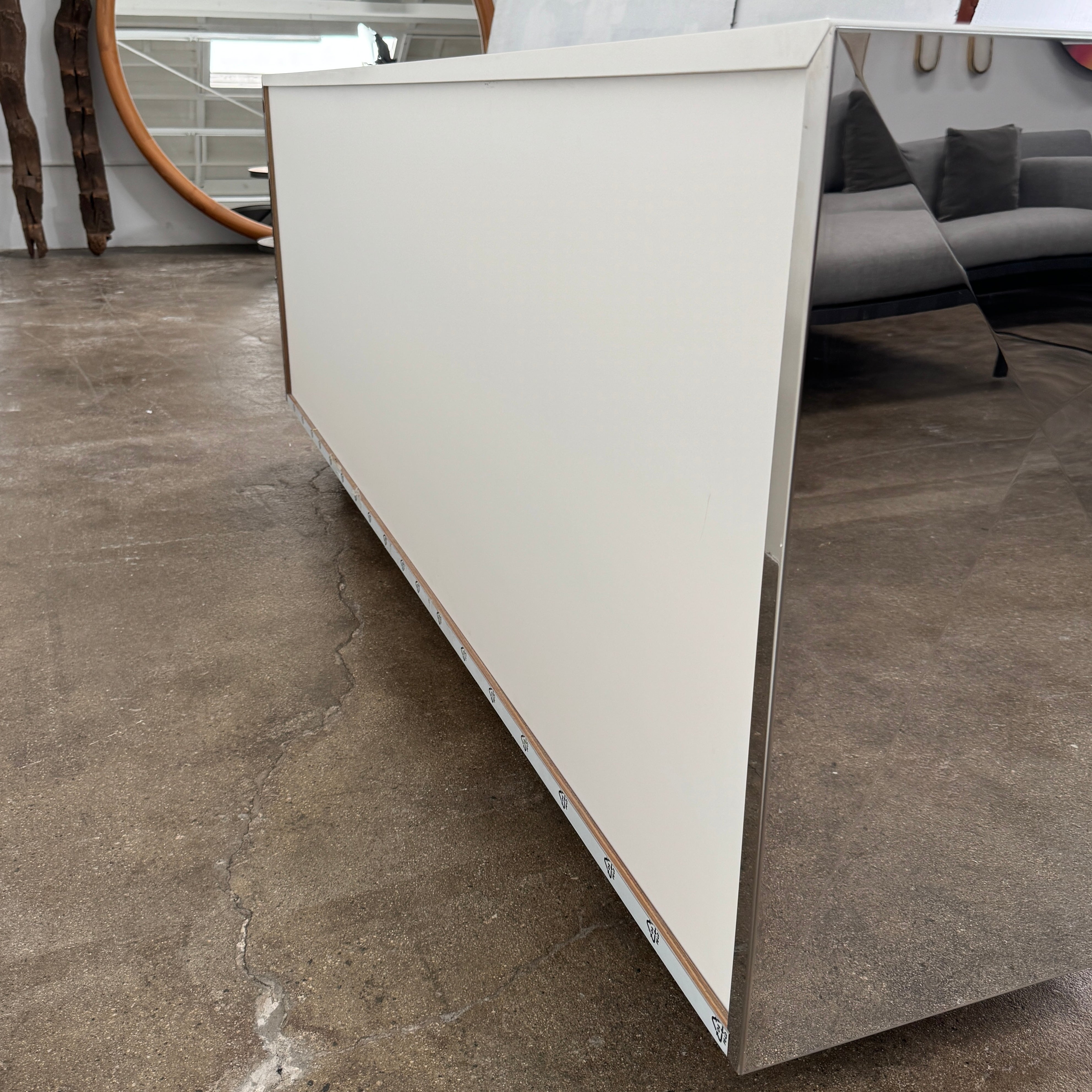 The Riflessi Cubric Sideboard by Riflessi features three mirrored doors and a geometric jagged top edge, shown here against a plain white wall on a concrete floor.