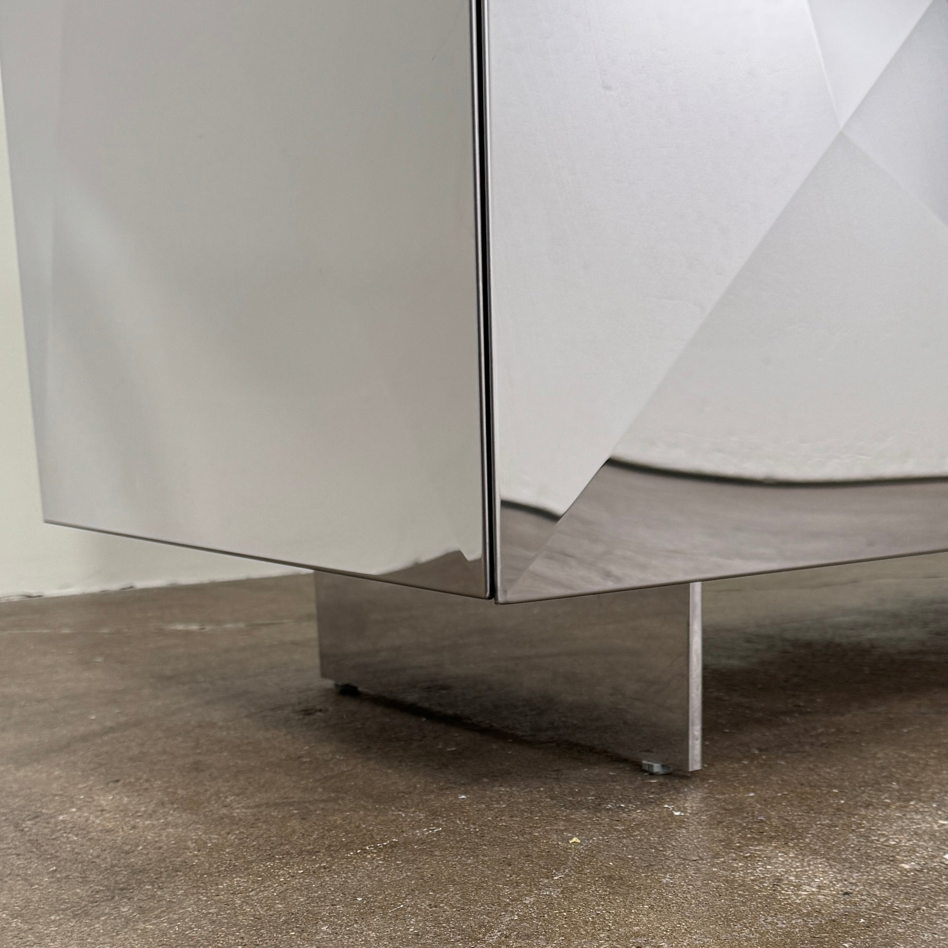The Riflessi Cubric Sideboard by Riflessi features three mirrored doors and a geometric jagged top edge, shown here against a plain white wall on a concrete floor.