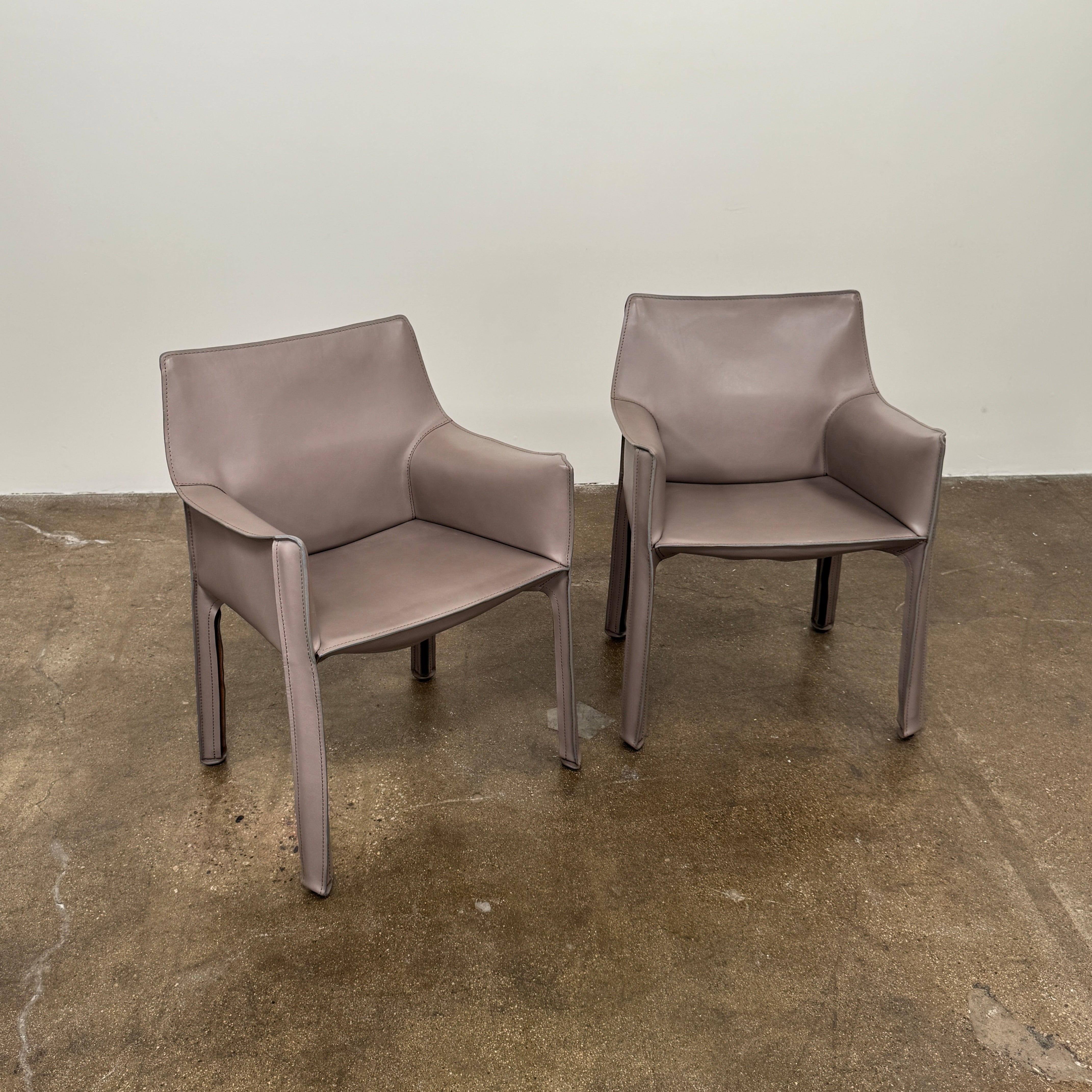 A pair of Cassina Cab 413 Dining Chairs by Modern Resale, featuring smooth taupe leather upholstery and straight legs, are placed side by side against a plain white background.