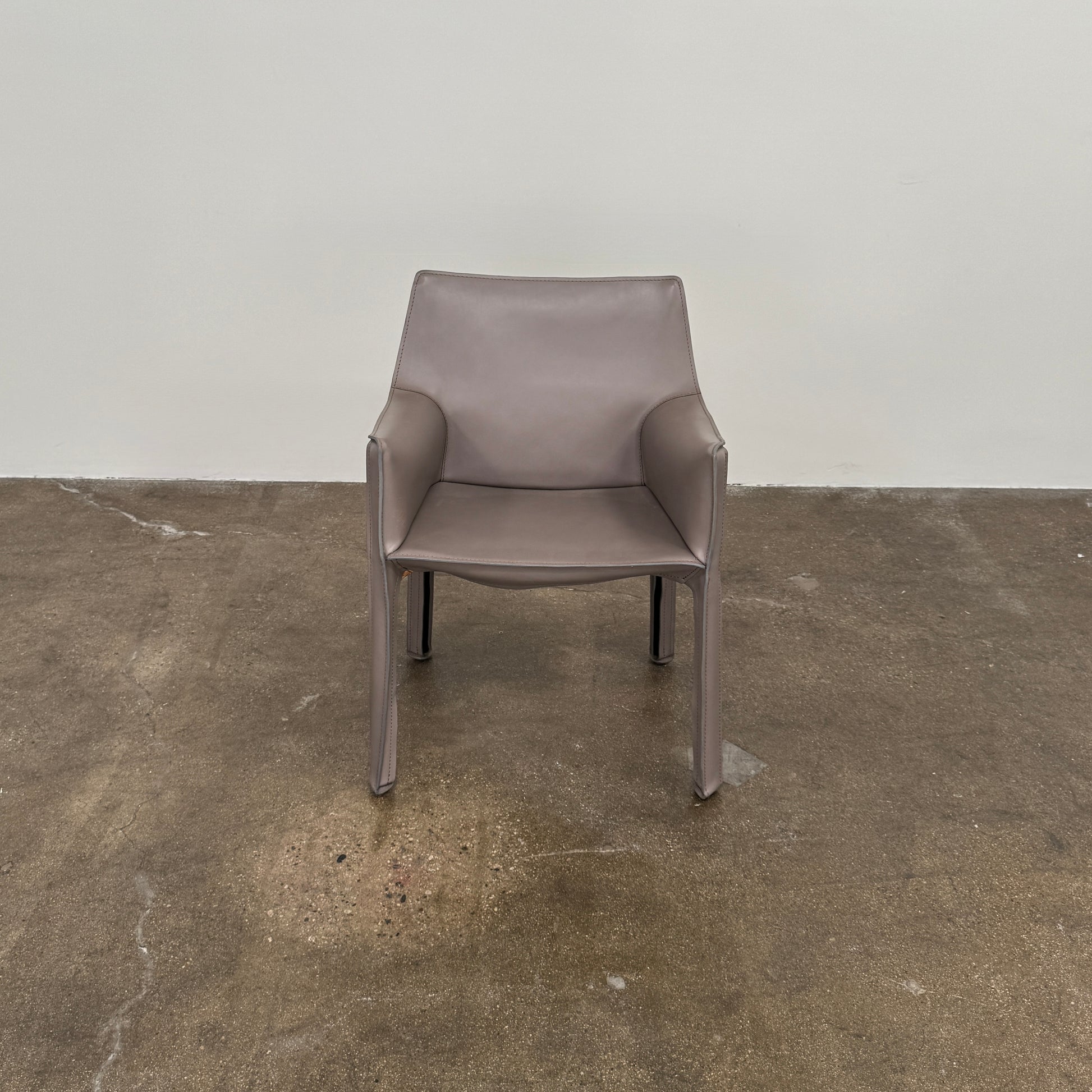 A pair of Cassina Cab 413 Dining Chairs by Cassina, featuring taupe leather and a modern design, are positioned side by side against a plain white background.