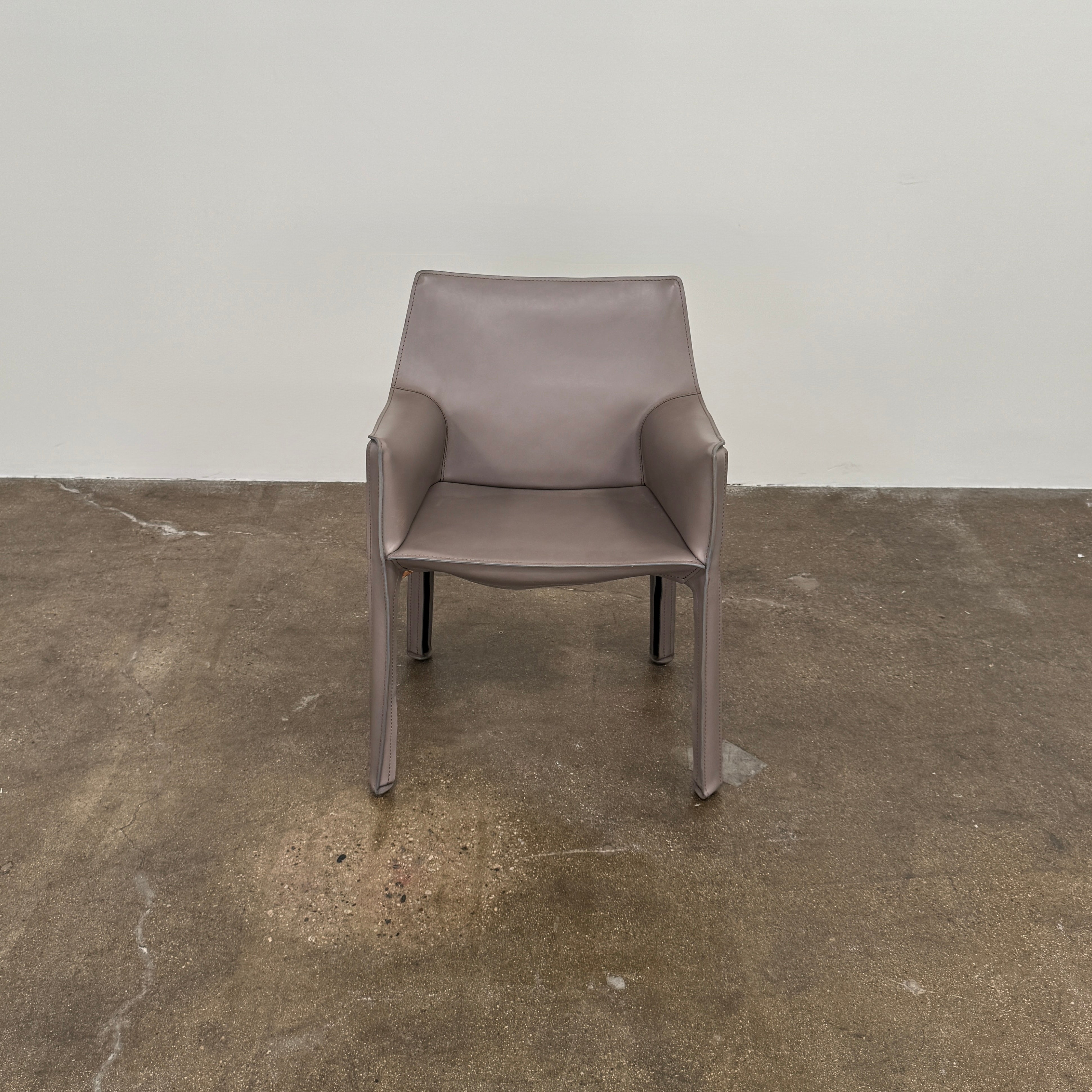 A pair of Cassina Cab 413 Dining Chairs by Cassina, featuring taupe leather and a modern design, are positioned side by side against a plain white background.