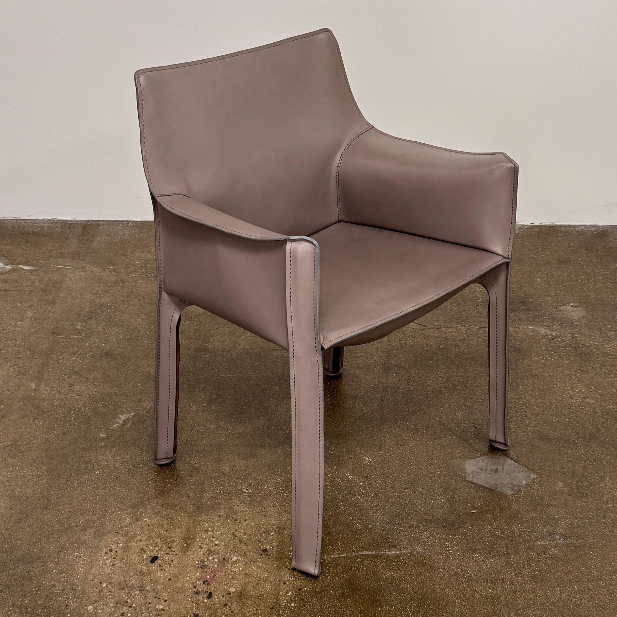 A pair of Cassina Cab 413 Dining Chairs by Cassina, featuring taupe leather and a modern design, are positioned side by side against a plain white background.