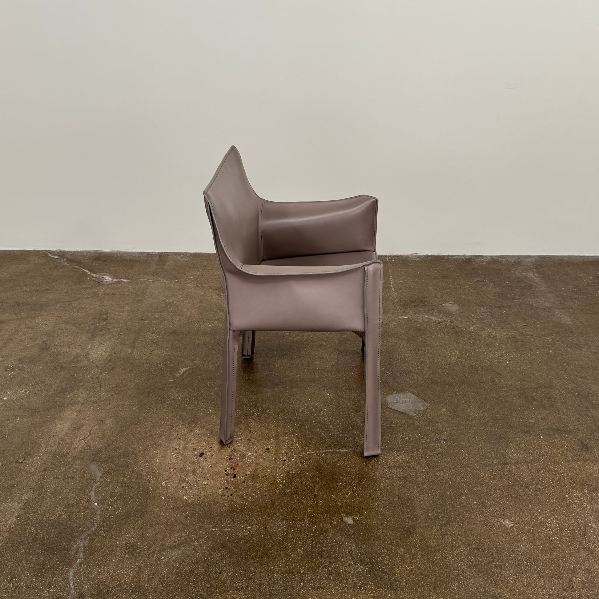 A pair of Cassina Cab 413 Dining Chairs by Cassina, featuring taupe leather and a modern design, are positioned side by side against a plain white background.