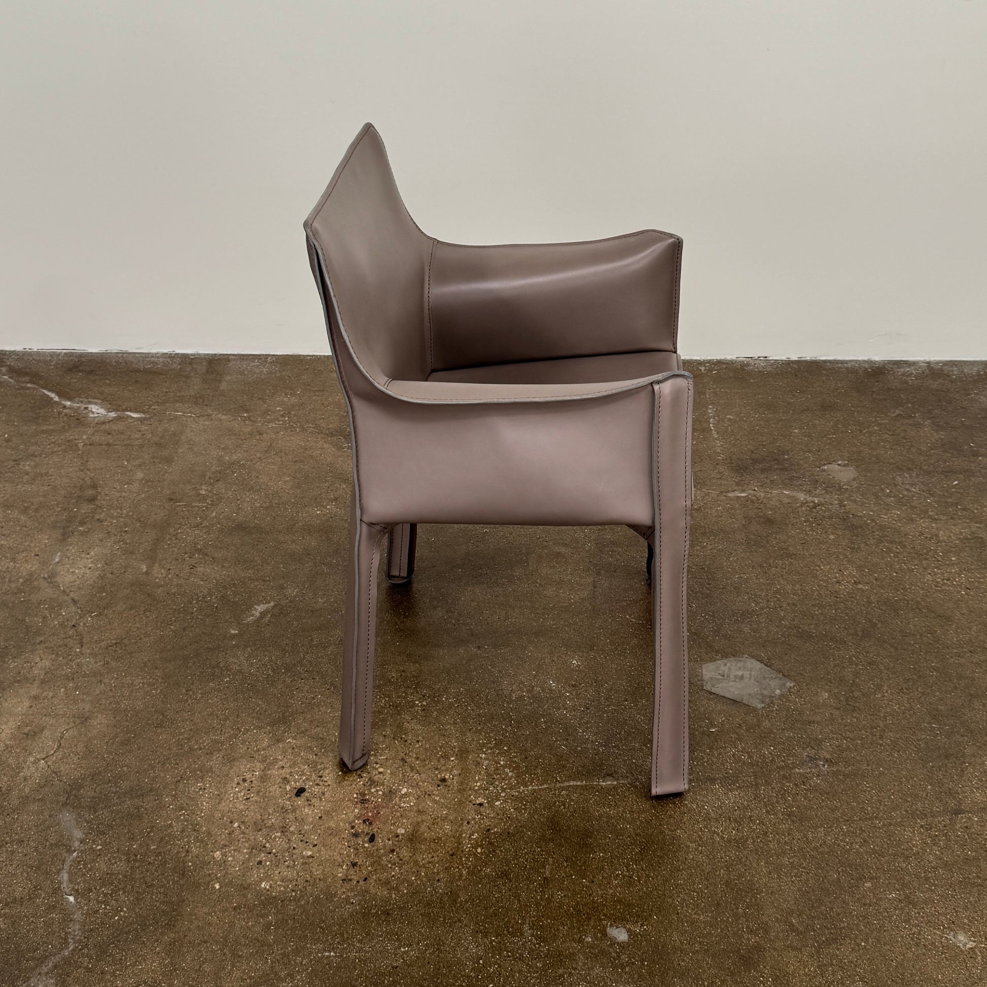 A pair of Cassina Cab 413 Dining Chairs by Cassina, featuring taupe leather and a modern design, are positioned side by side against a plain white background.