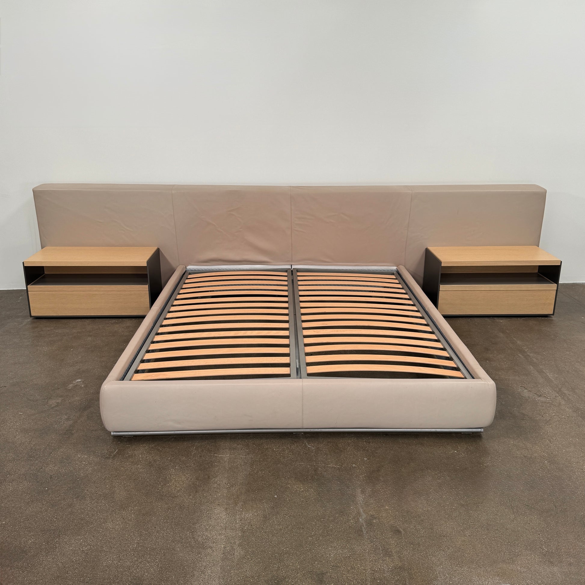 The Flexform Groundpiece Cal King Size Bed by Flexform features a beige upholstered leather frame, wide headboard, and exposed wooden slats, shown against a plain white background.