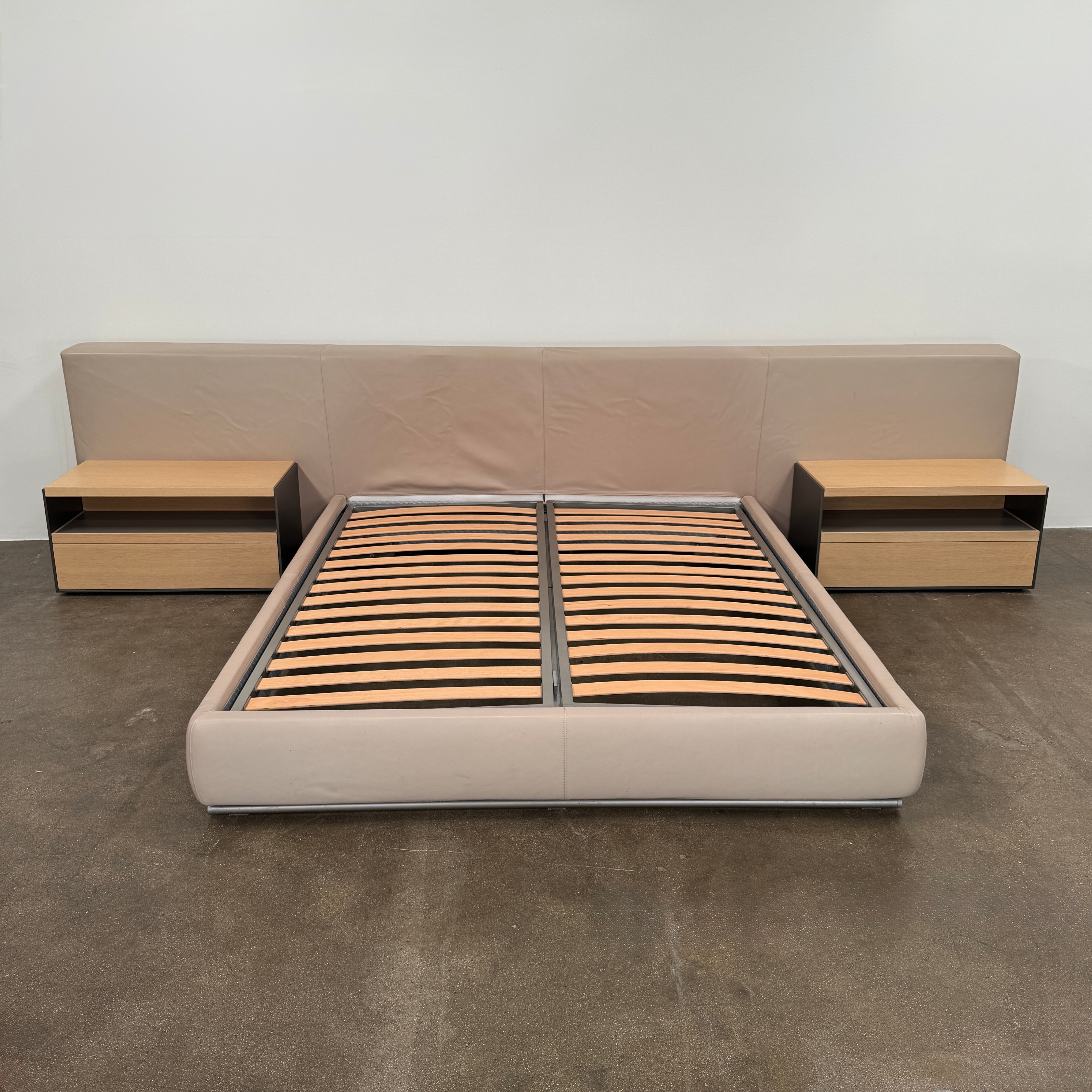 The Flexform Groundpiece Cal King Size Bed by Flexform features a beige upholstered leather frame, wide headboard, and exposed wooden slats, shown against a plain white background.