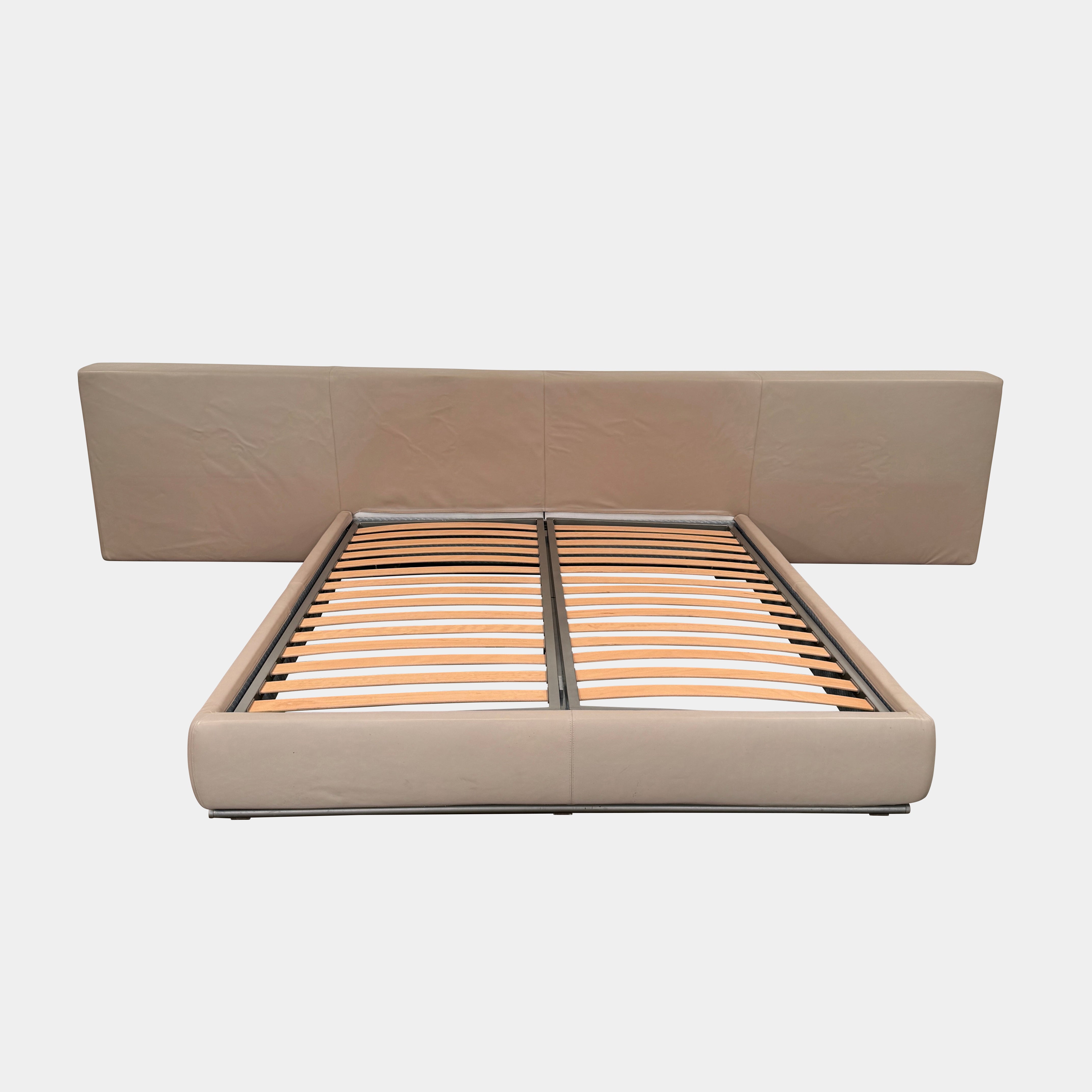 The Flexform Groundpiece Cal King Size Bed by Flexform features a beige upholstered leather frame, wide headboard, and exposed wooden slats, shown against a plain white background.