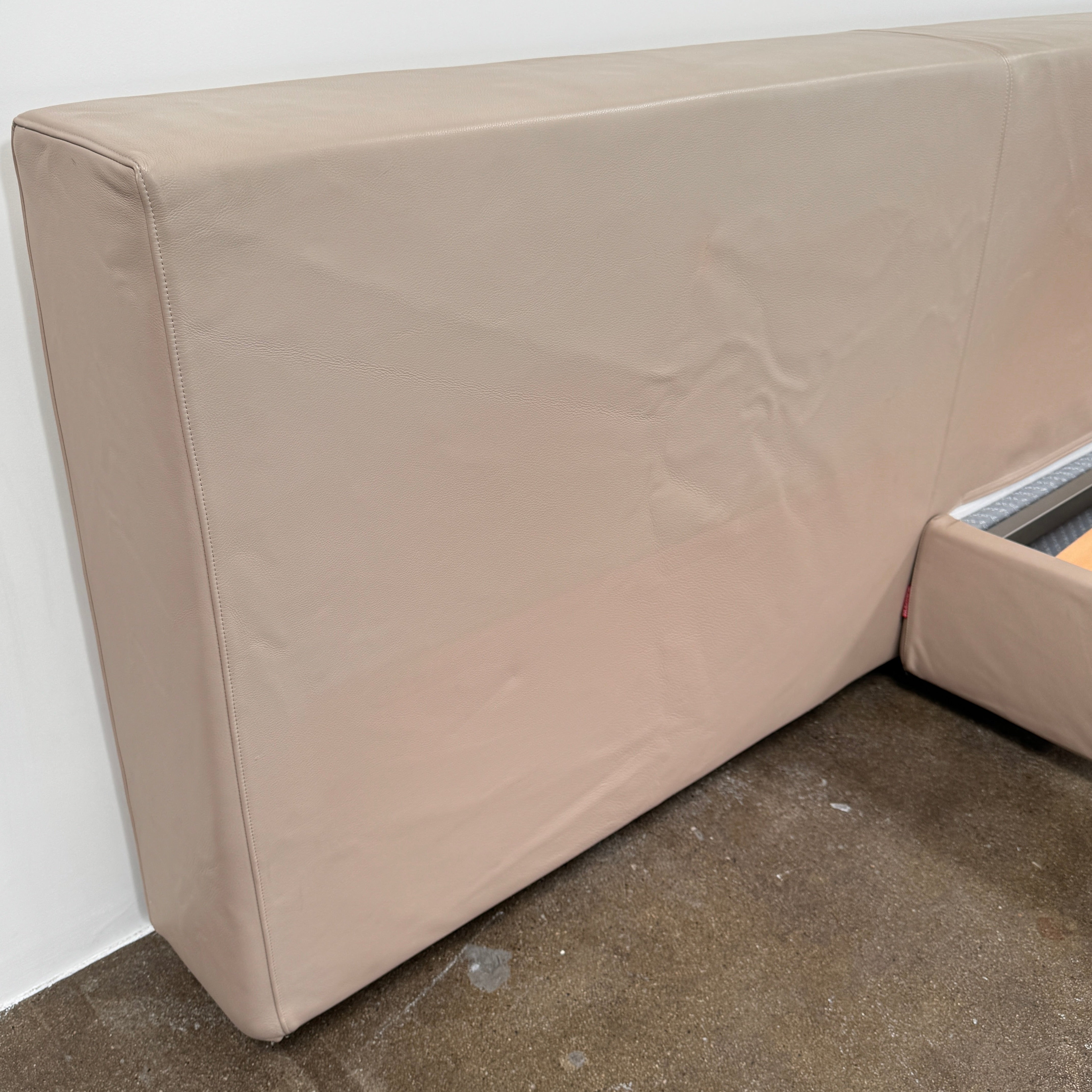 The Flexform Groundpiece Cal King Size Bed by Flexform features a beige upholstered leather frame, wide headboard, and exposed wooden slats, shown against a plain white background.