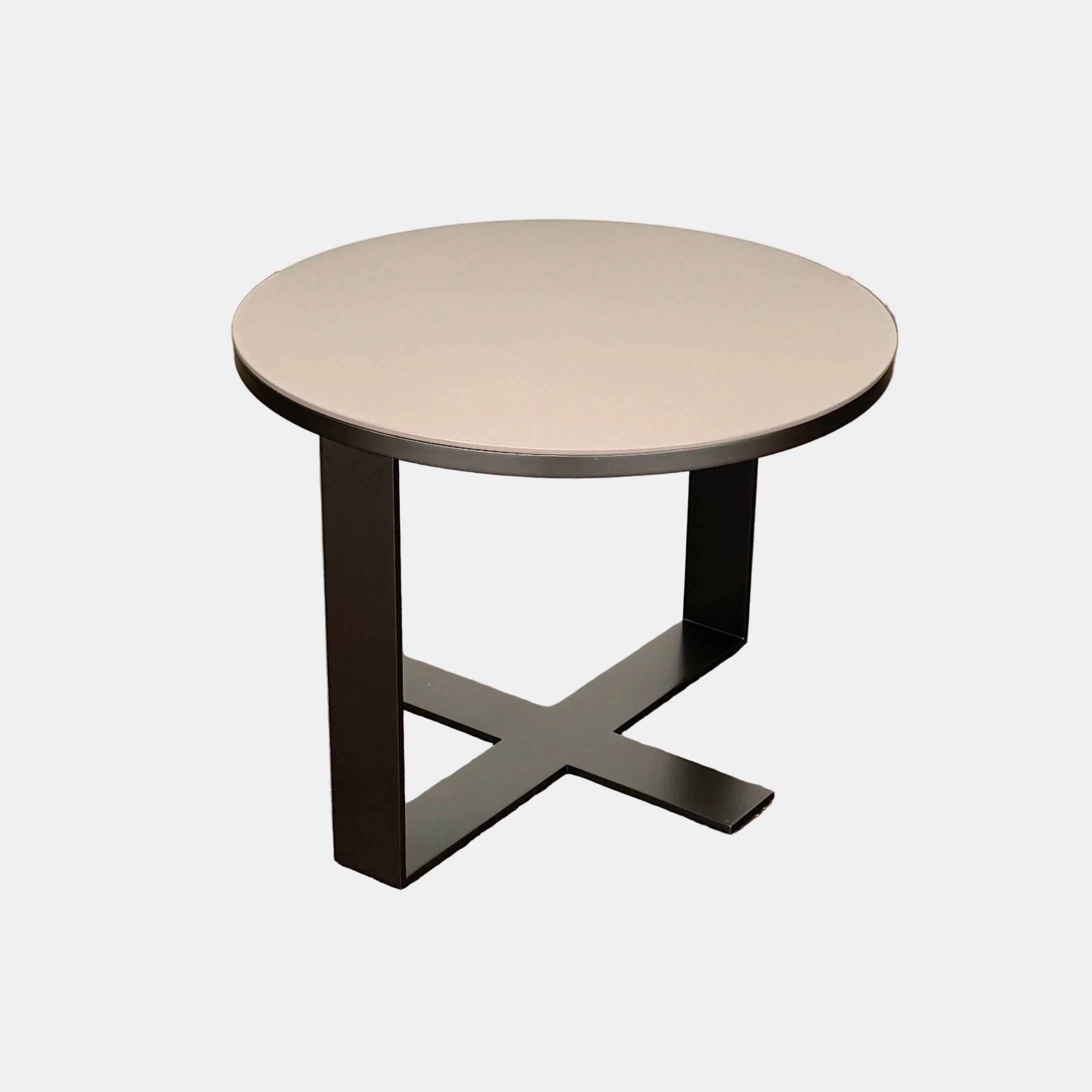 The B&B Italia Eileen Side Table, with its round gray top and single central metal leg, stands on a brown concrete floor against a plain white wall—ideal as a modern nightstand.