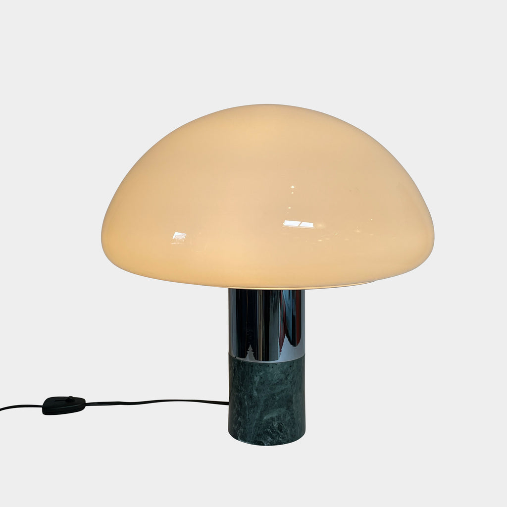 The Nahoor K&W Table Light features a large, dome-shaped beige shade and a cylindrical base crafted with exquisite Murano glass. This elegant piece reflects Italian design and sophistication, complete with a black power cord and switch.