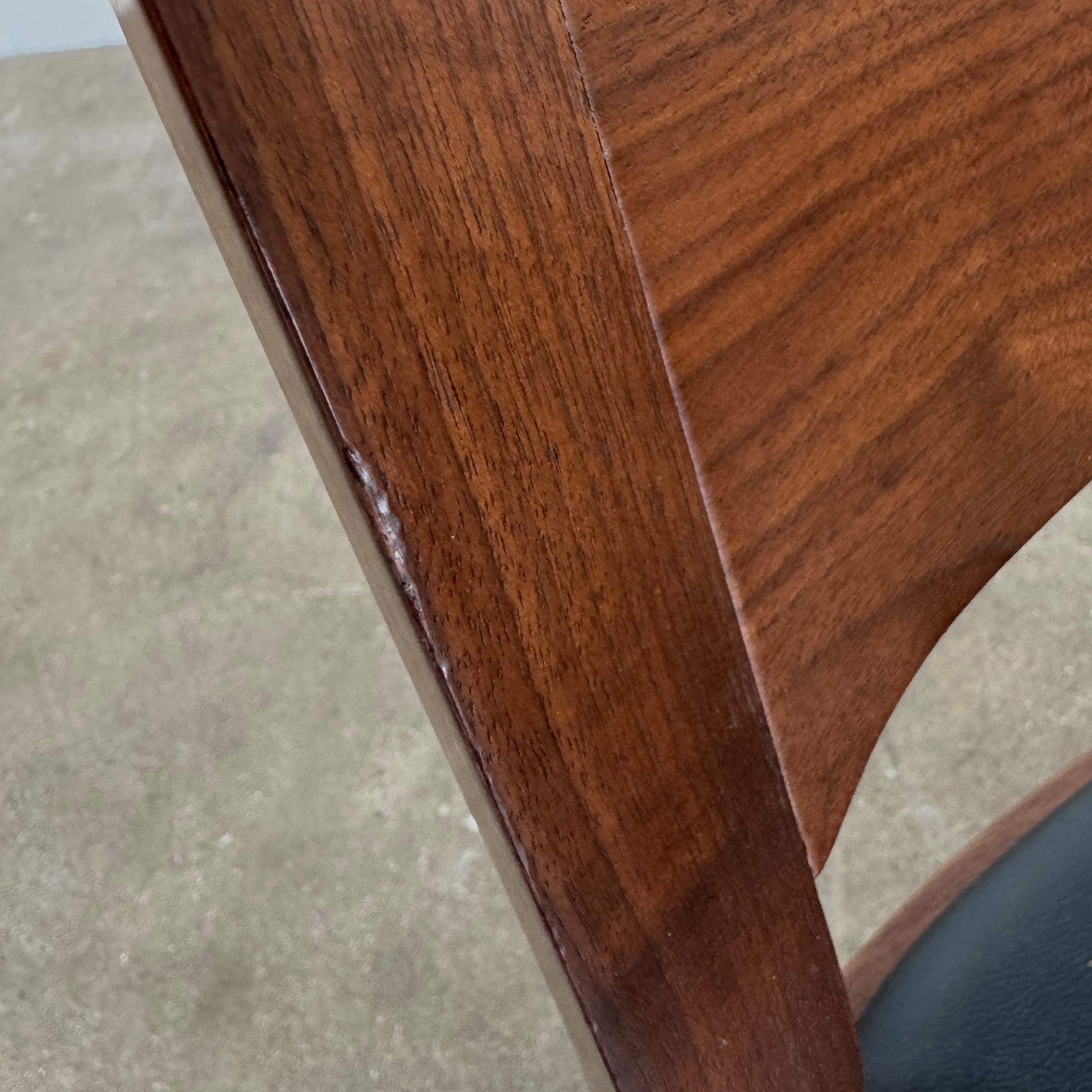 The Case Profile Dining Chair Set of 4 by Case, featuring wooden frames and black cushioned seats, is arranged on a concrete floor against a plain off-white wall.